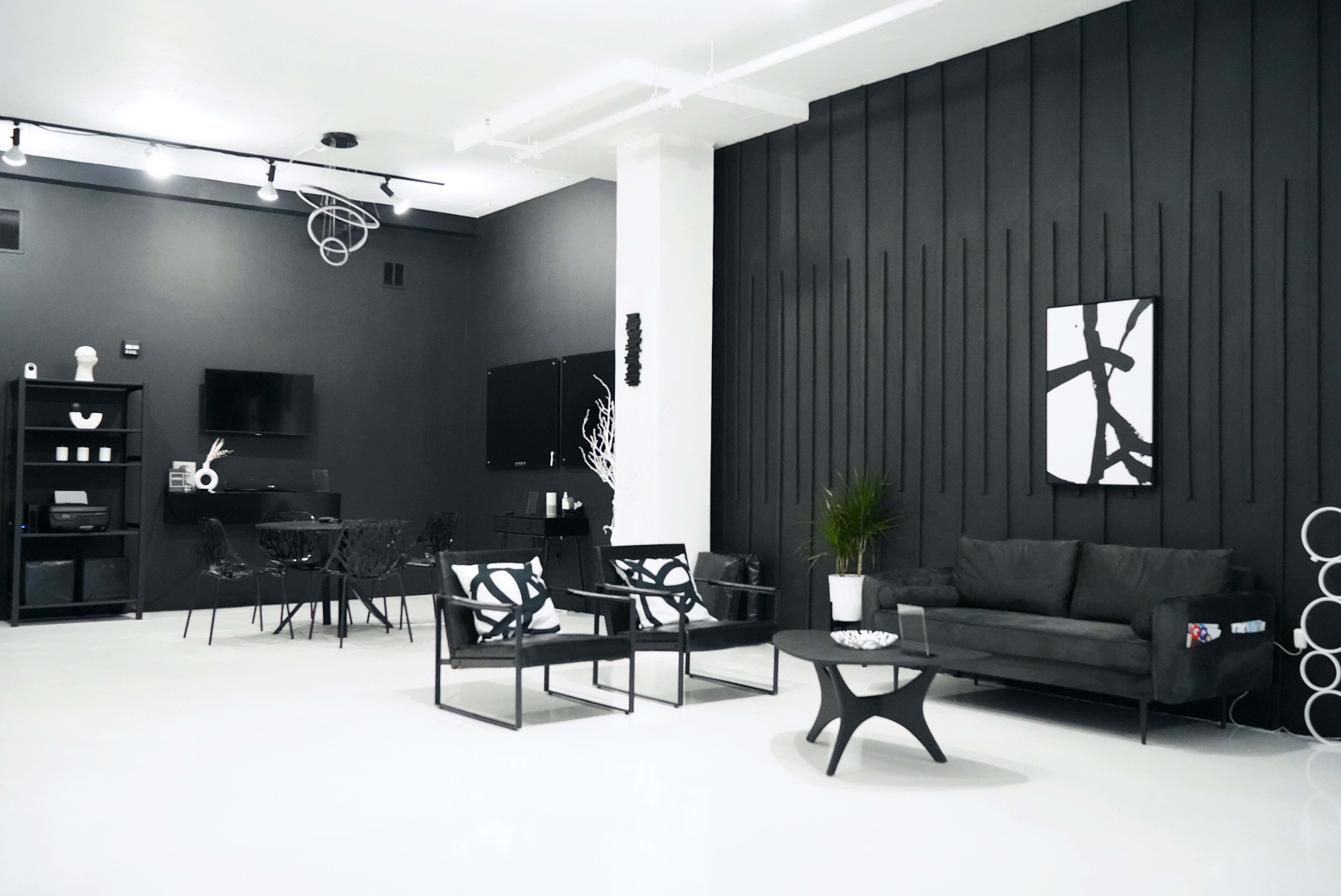 A modern room with black walls, white flooring, minimalist furniture, and a sleek design aesthetic.