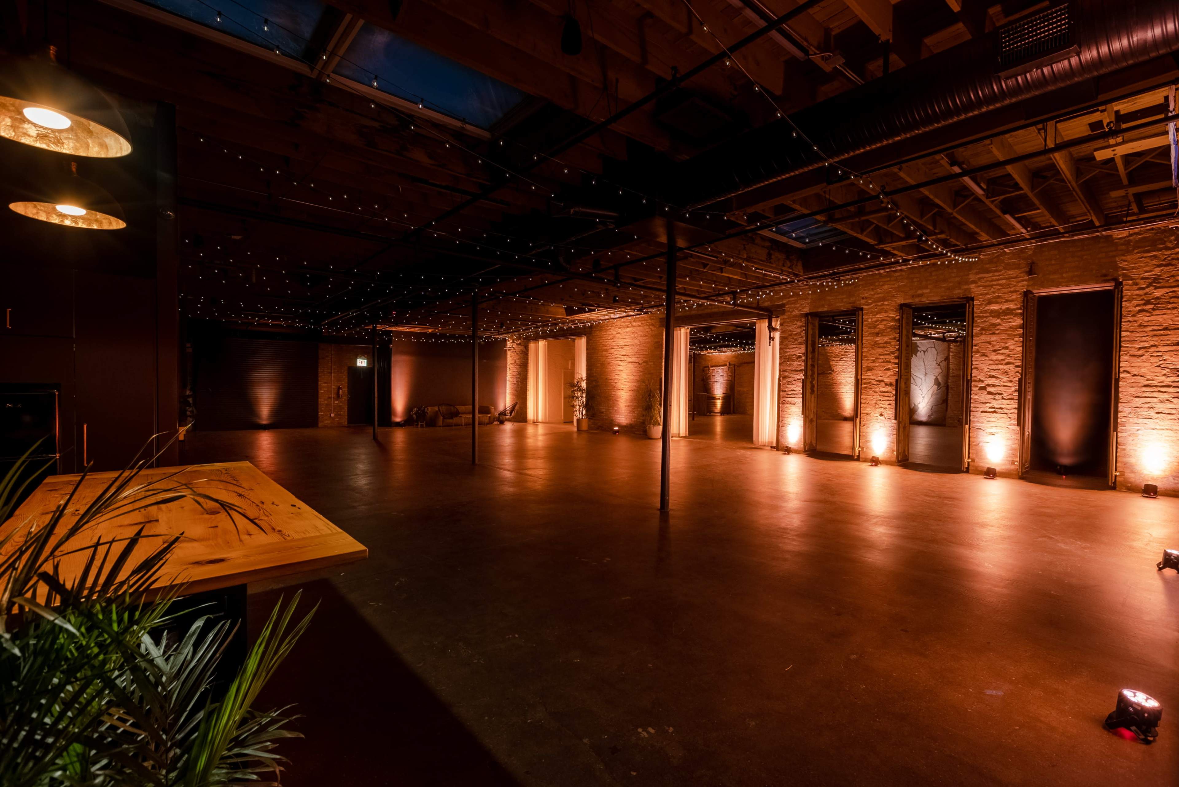 The image shows an empty indoor venue with exposed wooden beams, stone walls, and warm lighting.