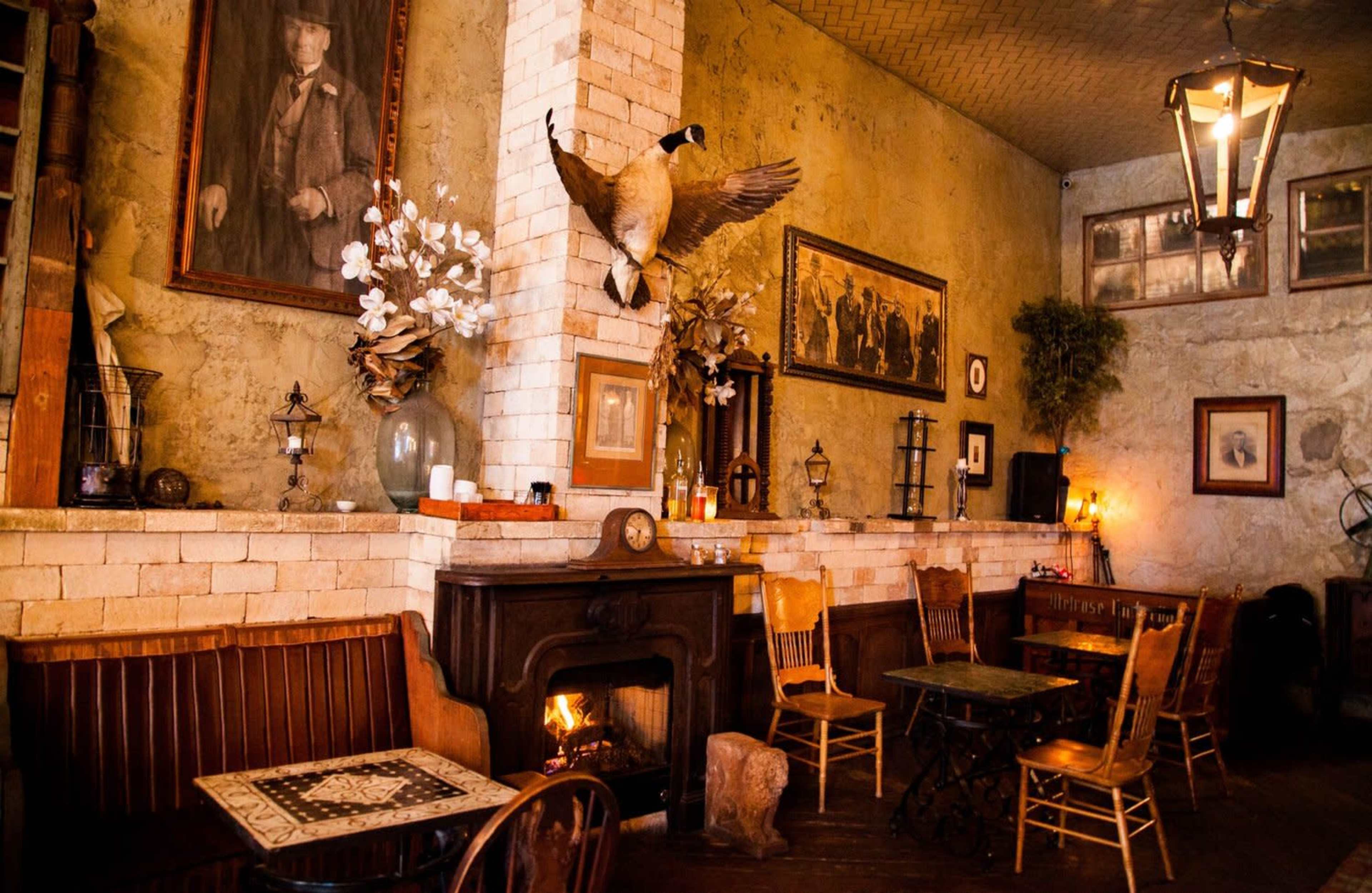 A cozy, rustic interior of a pub or restaurant featuring wooden furniture, a fireplace, and mounted taxidermy on the wall.