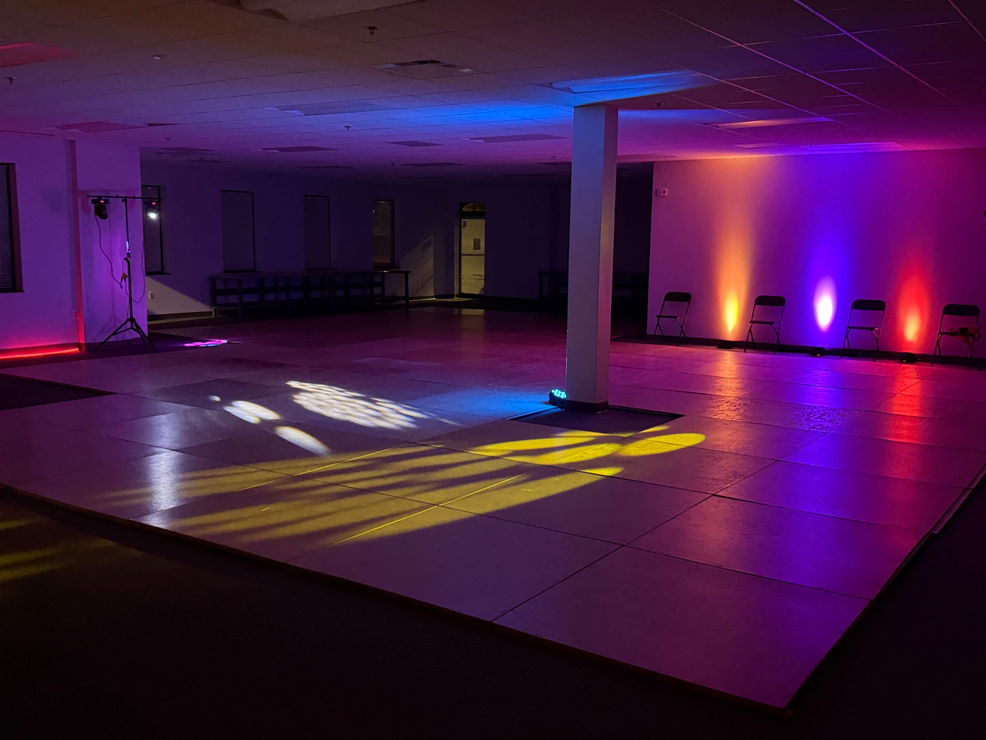The image shows a spacious, empty room with a polished floor, illuminated by colorful lights and cast shadows.
