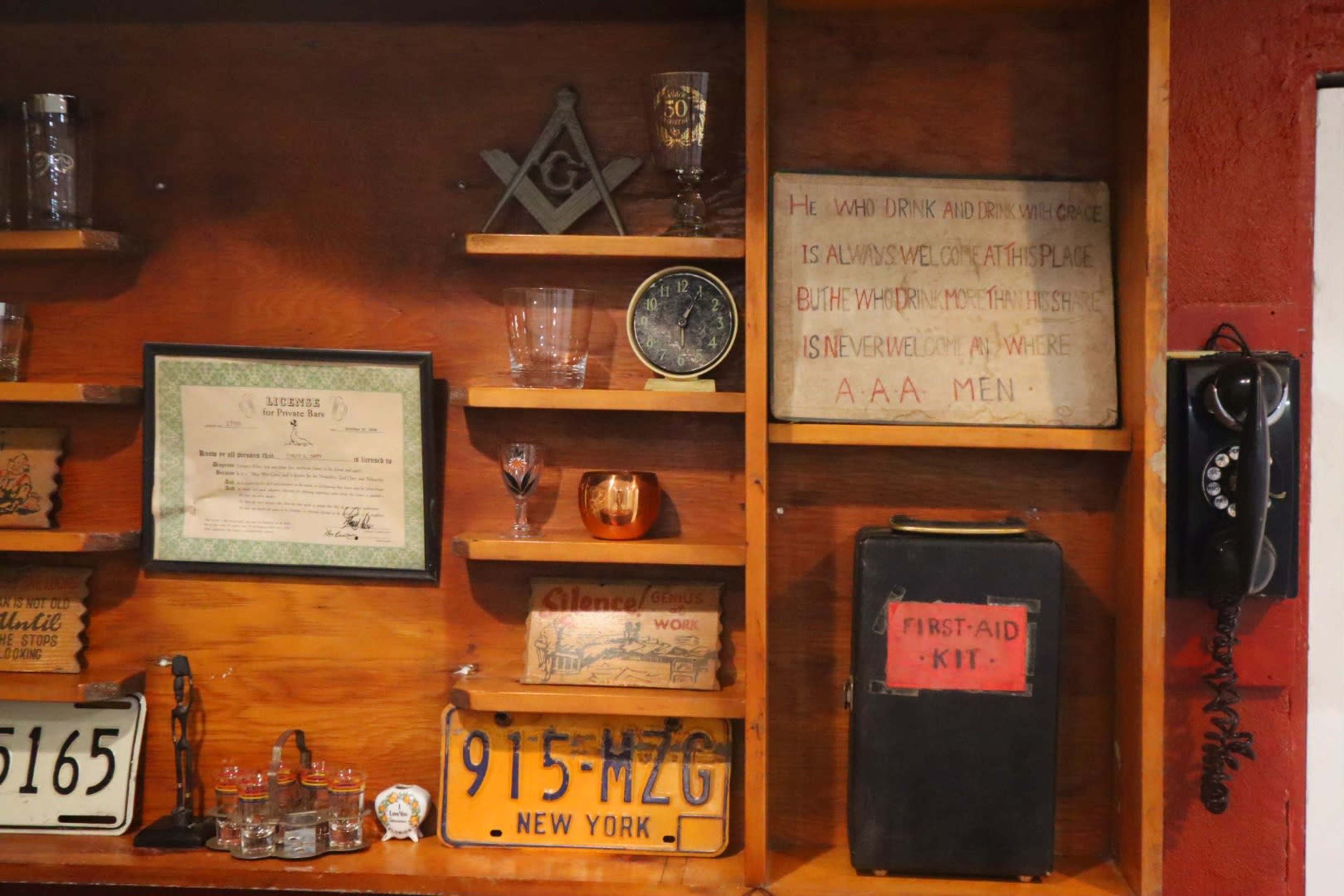 A wooden display shelf filled with various vintage items, including glassware, an old telephone, and decorative plaques.