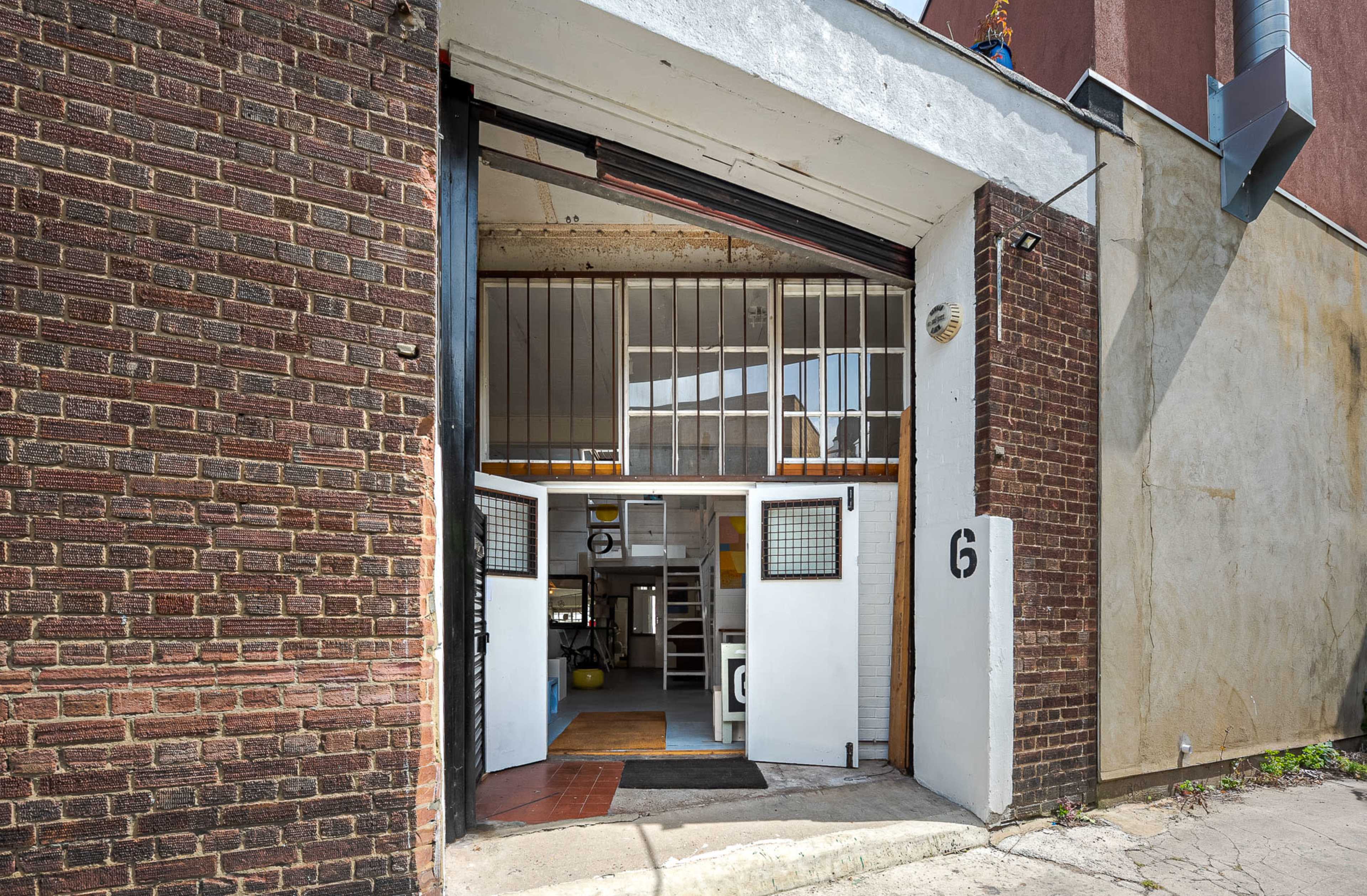 A large, open doorway with metal bars, leading into an industrial-style interior with exposed brick walls.