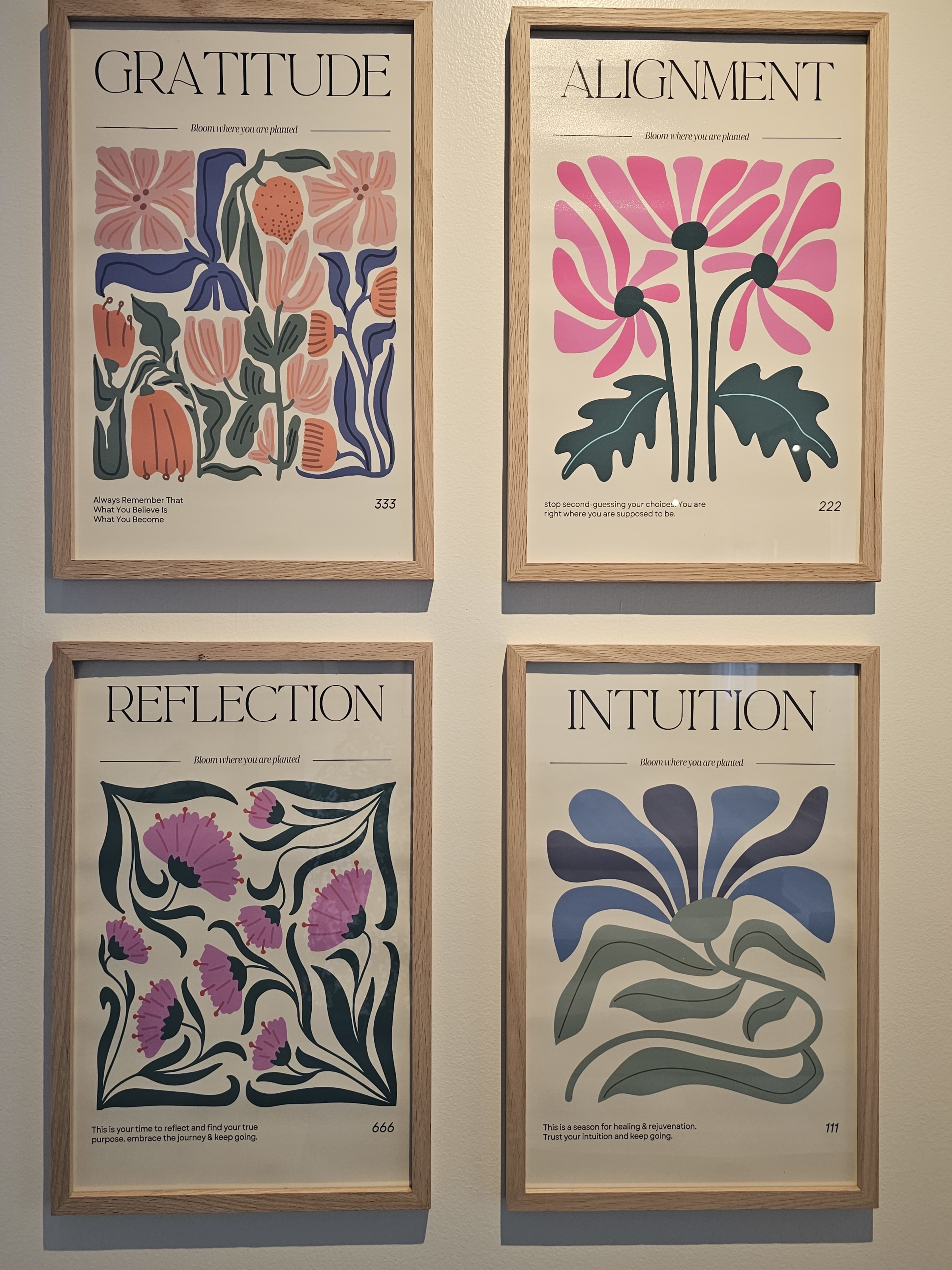 The image features four decorative art prints framed on a wall, each labeled with titles: "Gratitude," "Alignment," "Reflection," and "Intuition."