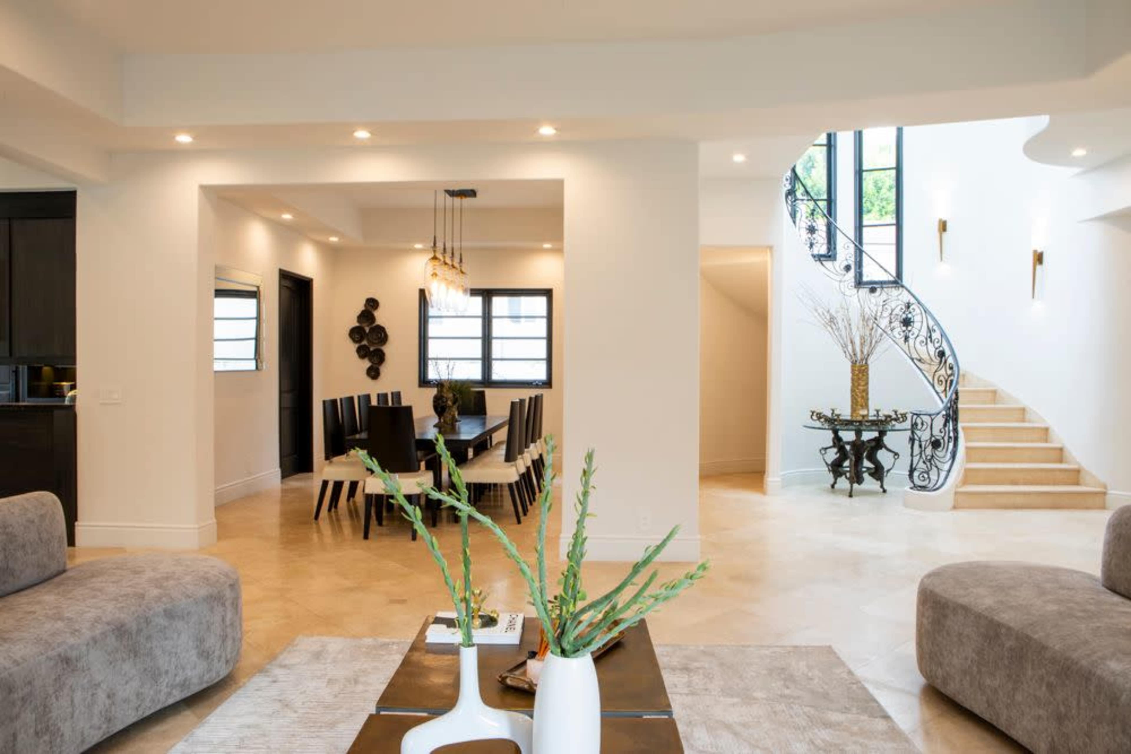 A spacious, elegantly designed living area leading to a dining room and a staircase.