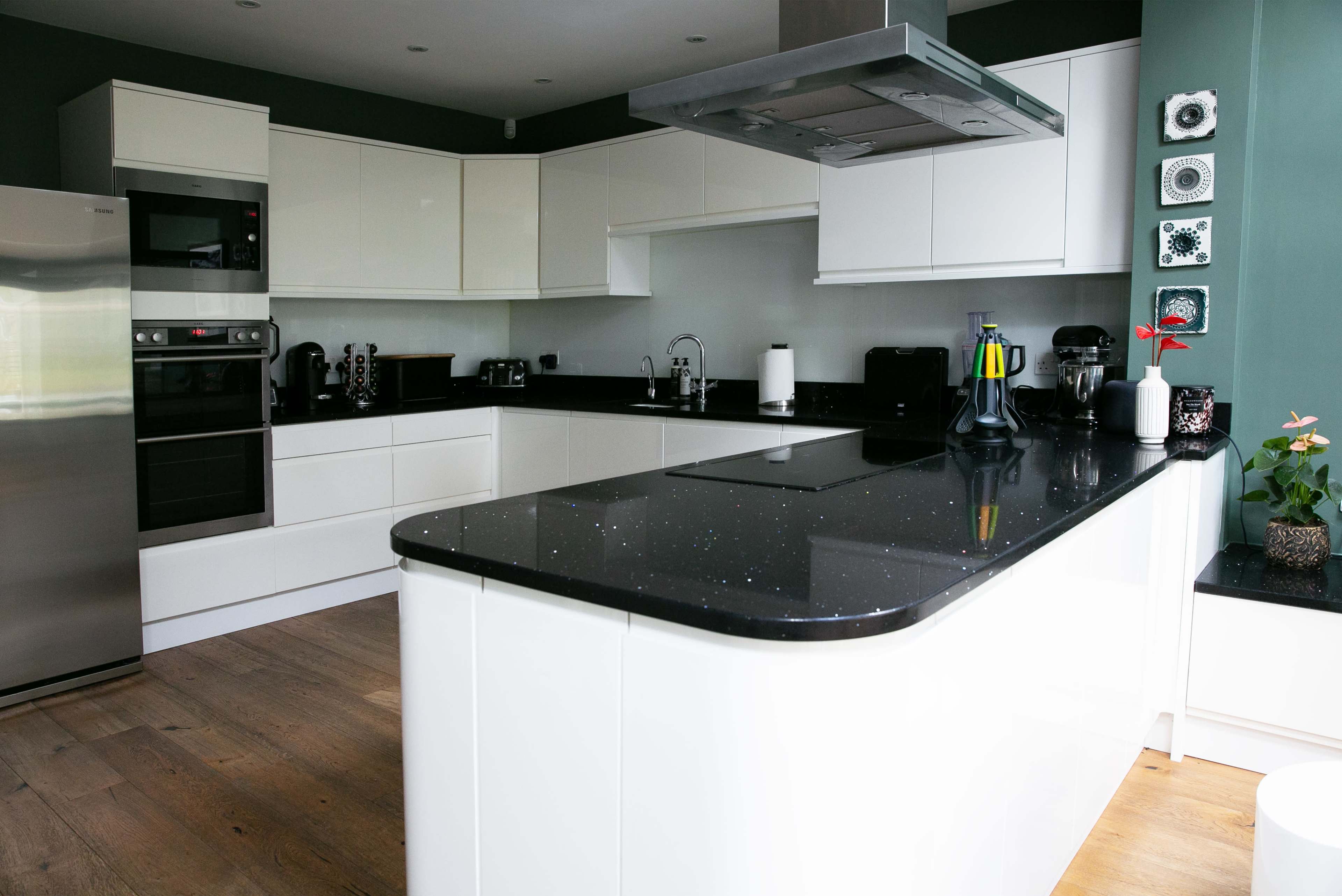 The image shows a modern kitchen featuring white cabinetry, a black countertop, and stainless steel appliances.