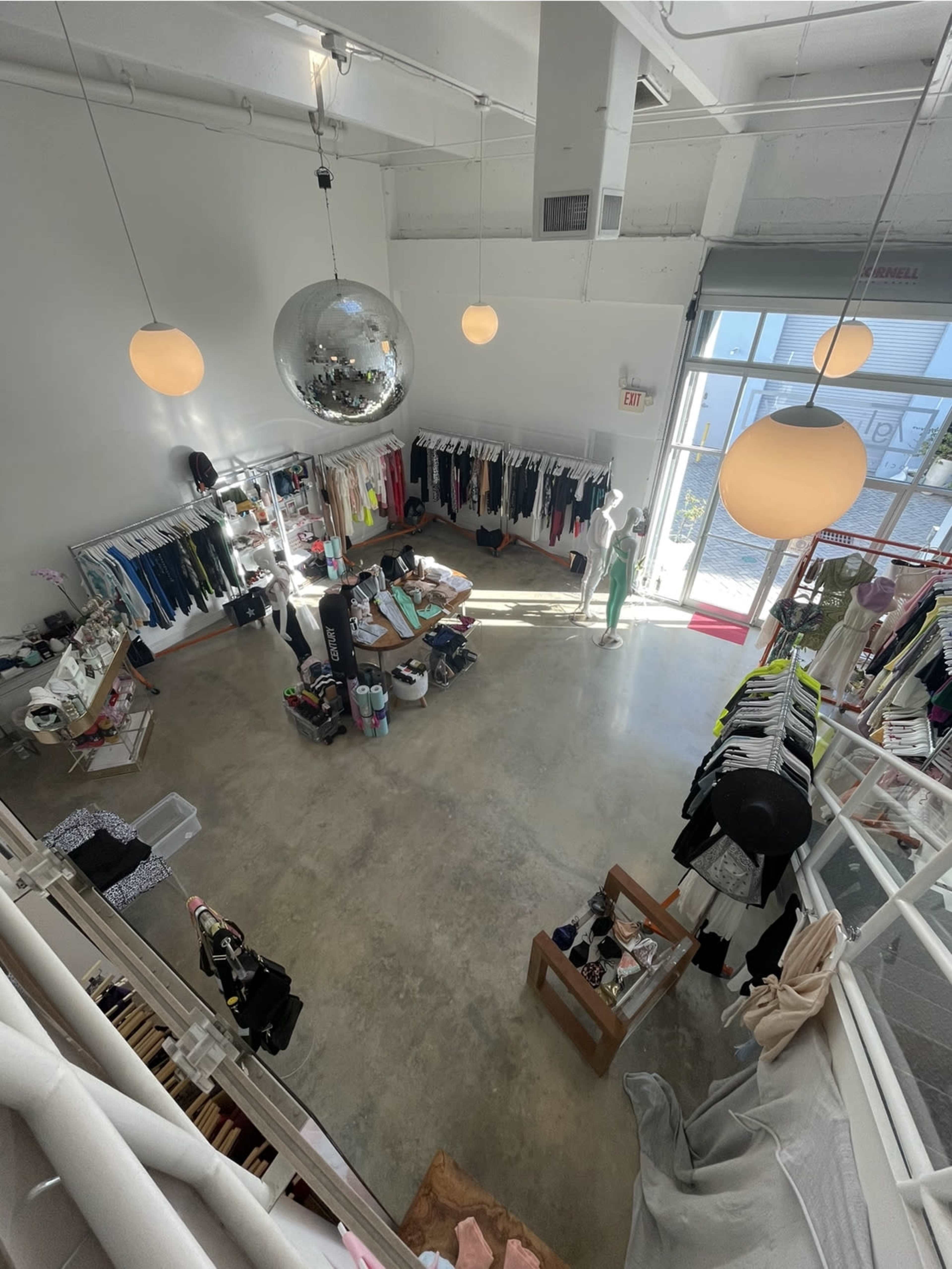 The image shows a clothing store with various apparel displayed on racks and shelves, featuring a large disco ball and overhead lighting.
