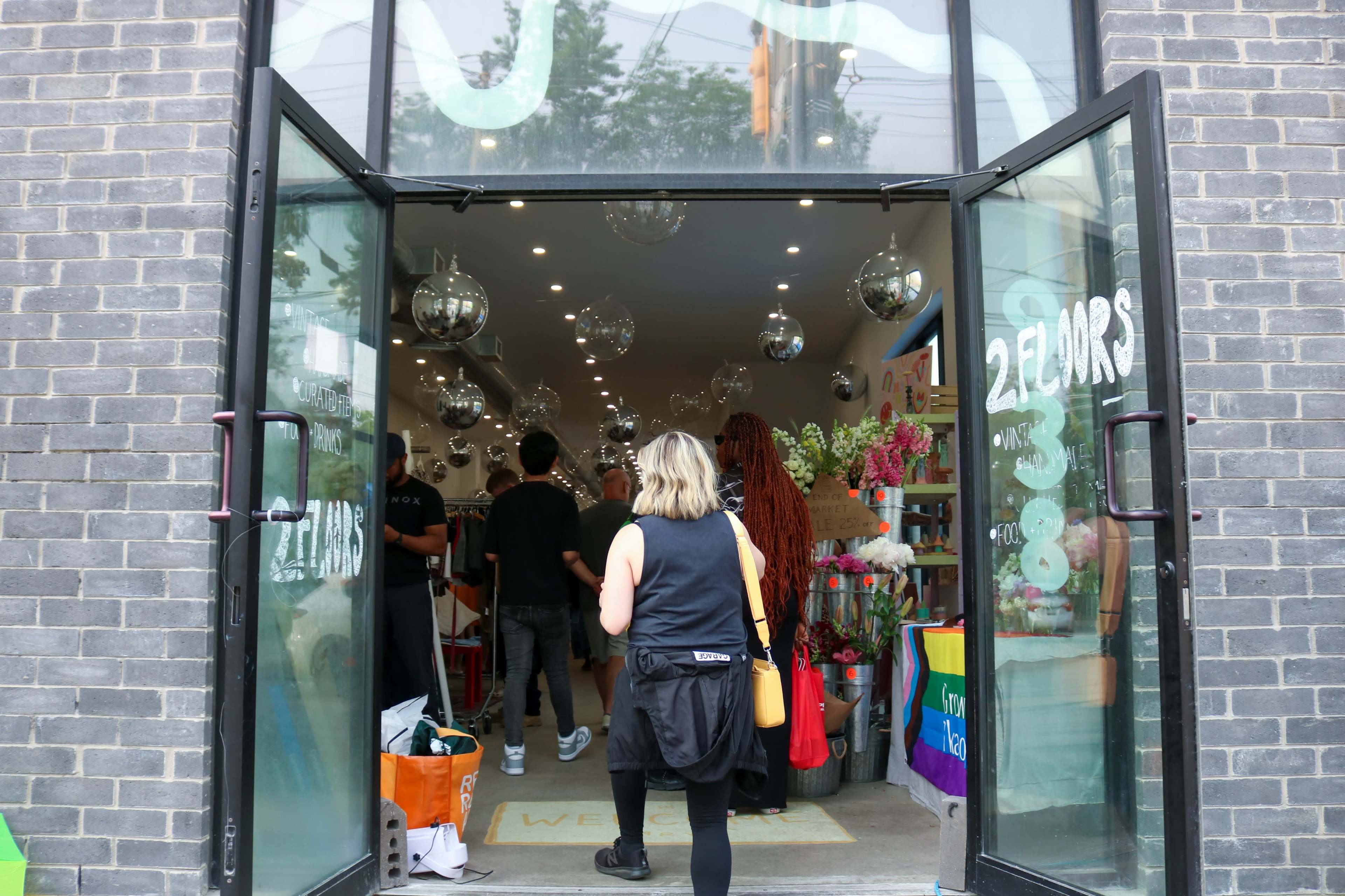 A woman enters a brightly lit shop with decorative items and colorful displays while several people browse inside.