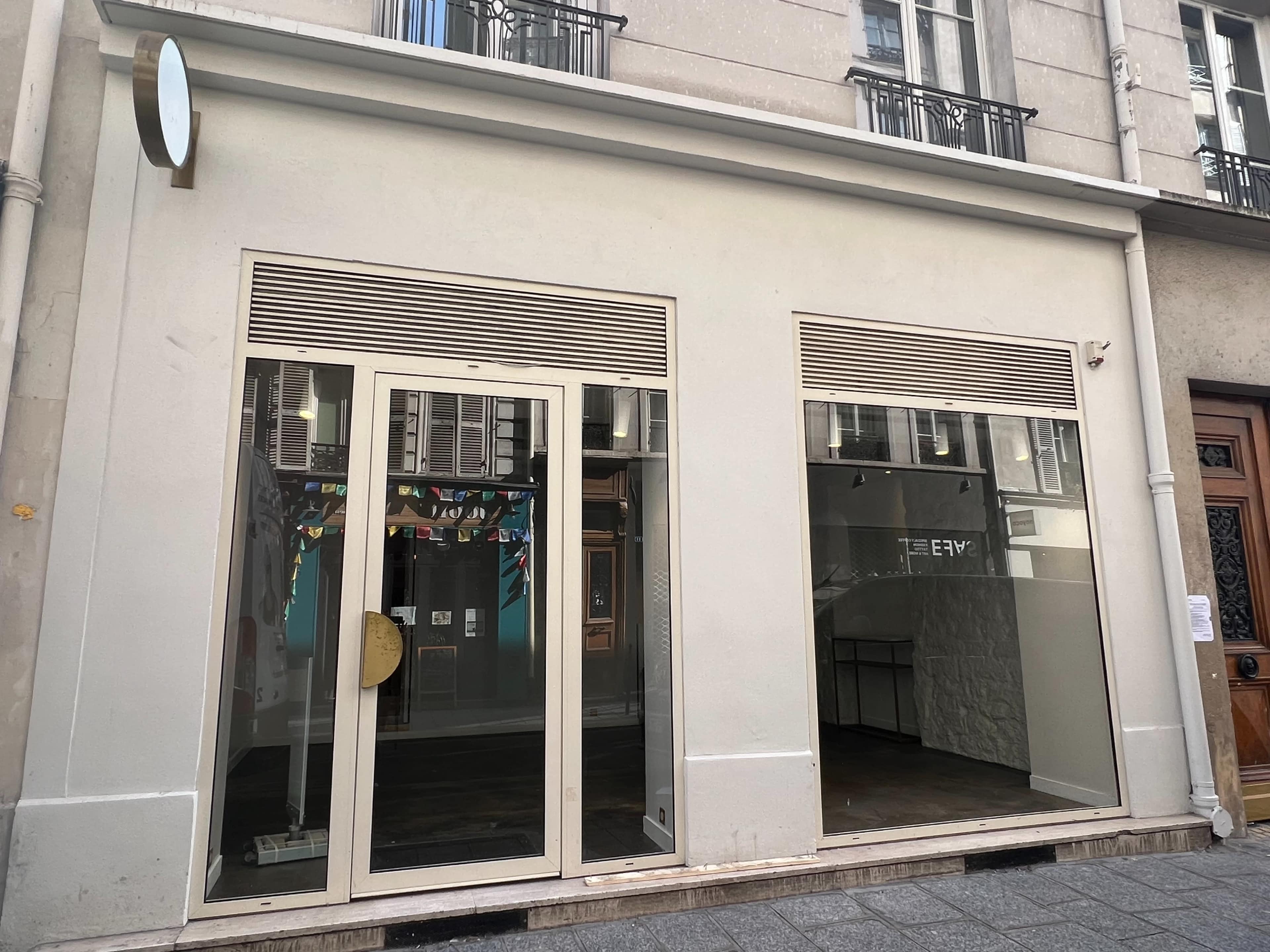 The image shows a storefront with large glass doors and windows, featuring a plain exterior and minimal signage.