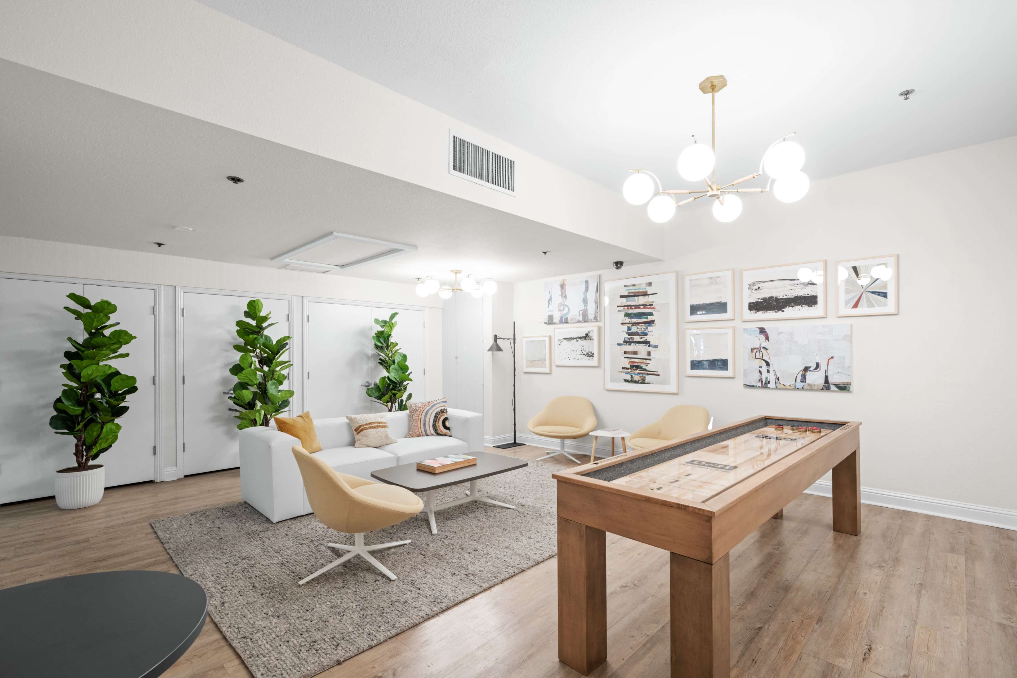 A modern lounge area features a cozy seating arrangement, a game table, and framed artwork on the walls.