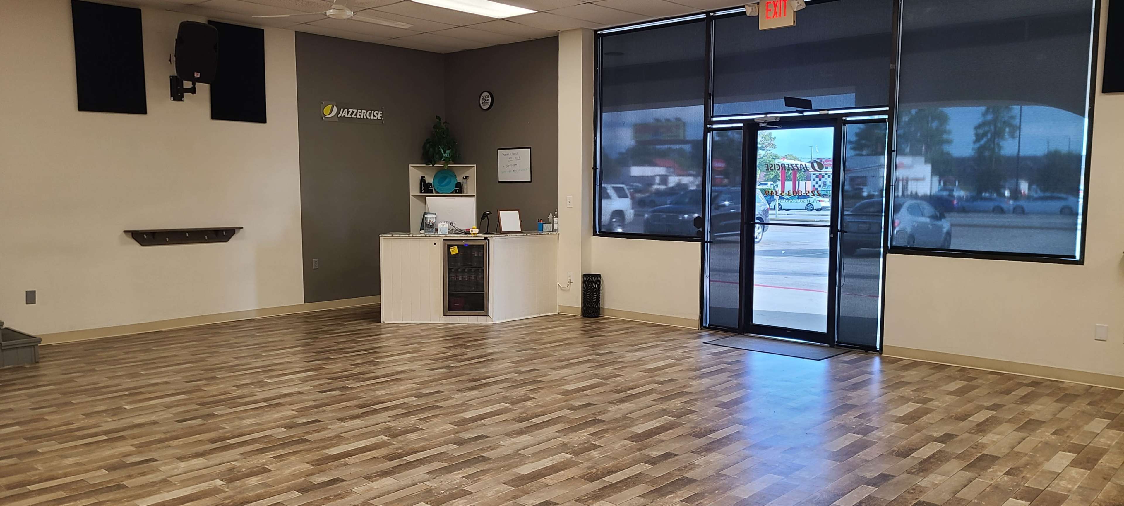 The image shows a spacious interior of a business, featuring a reception area with a counter and a large entryway leading to an exterior view.