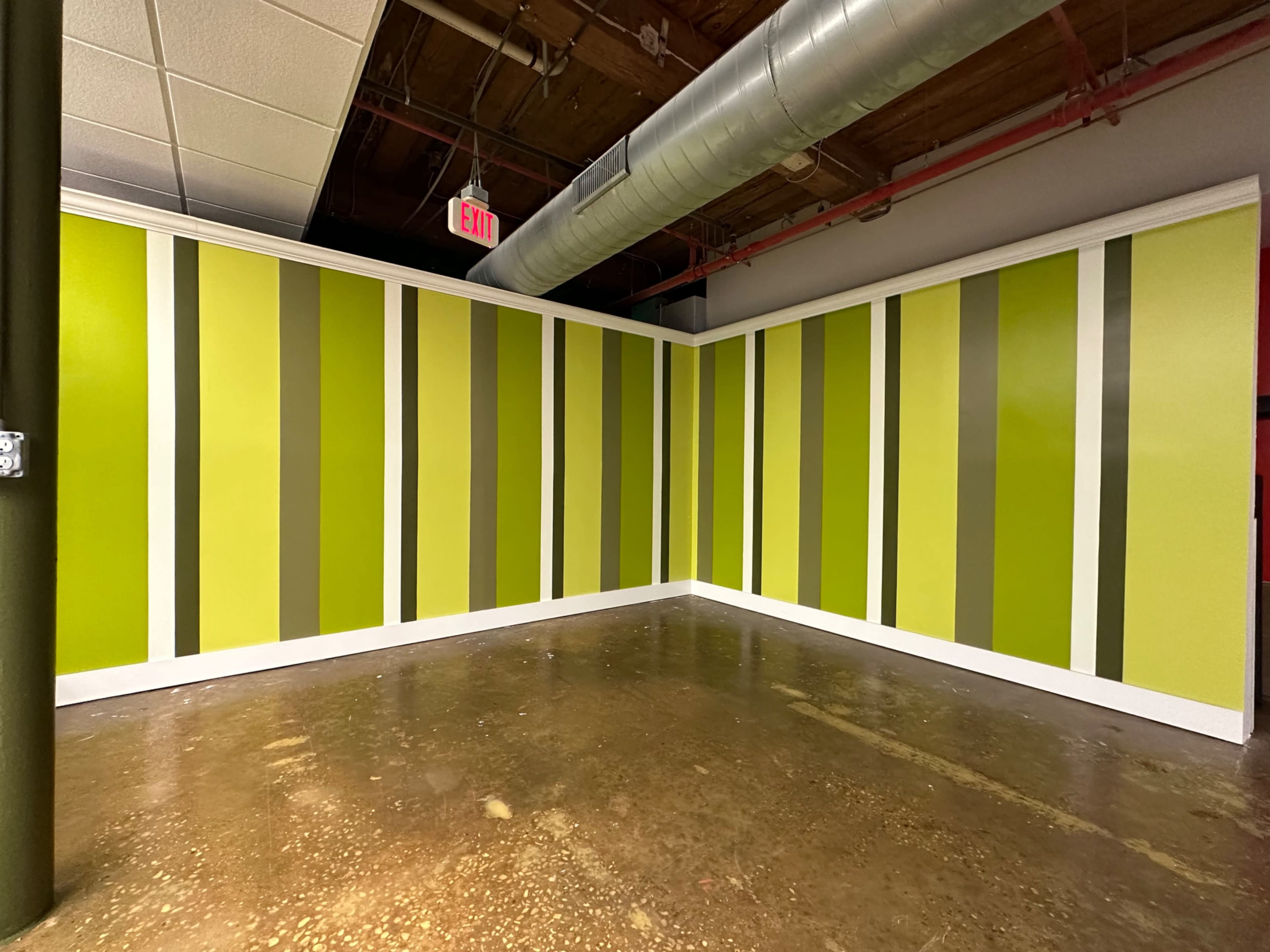 An interior corner of a room featuring walls painted in alternating shades of green with white trim.