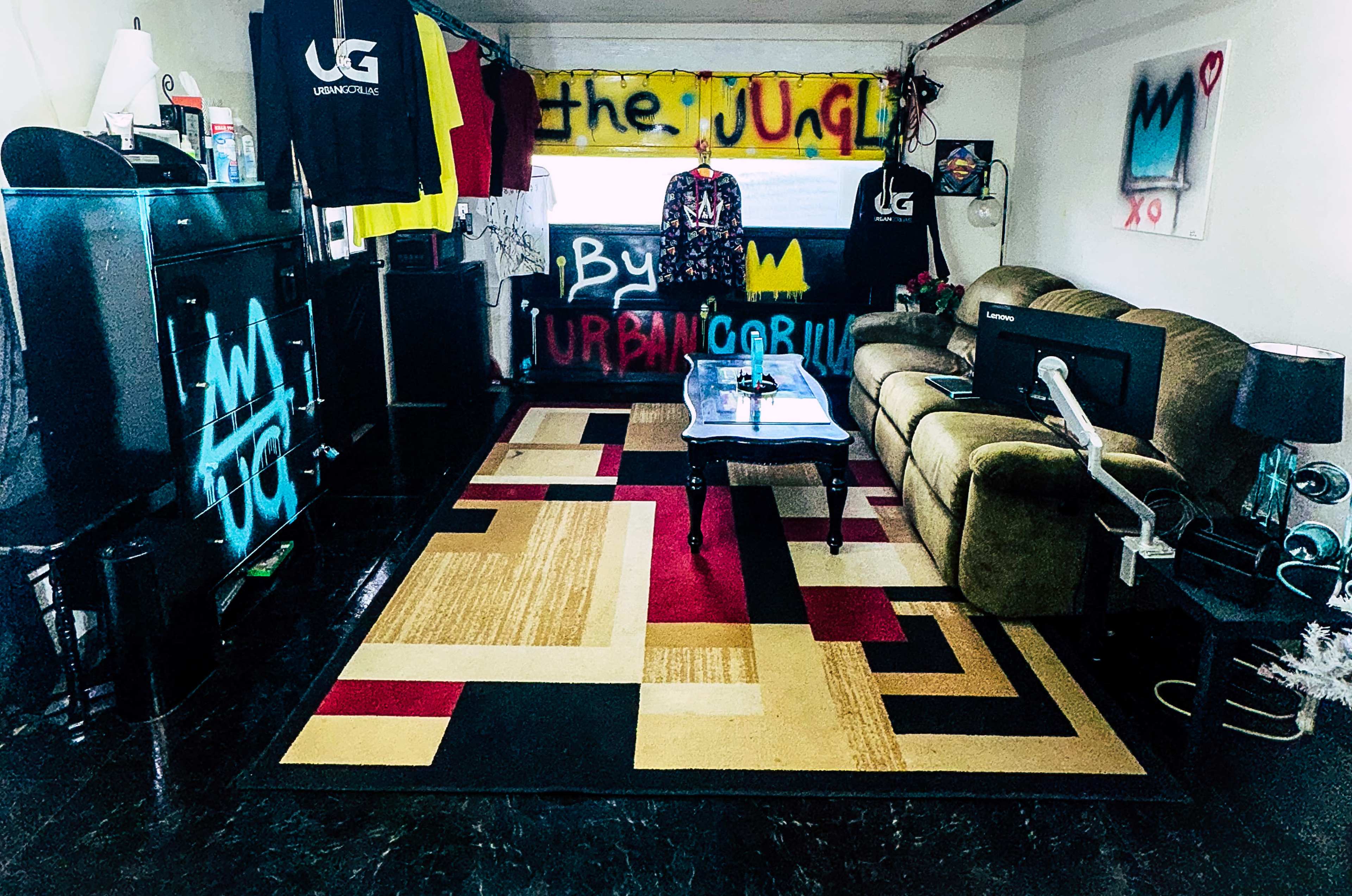 A room with a green sofa, a coffee table on a patterned rug, and walls adorned with colorful graffiti and art.