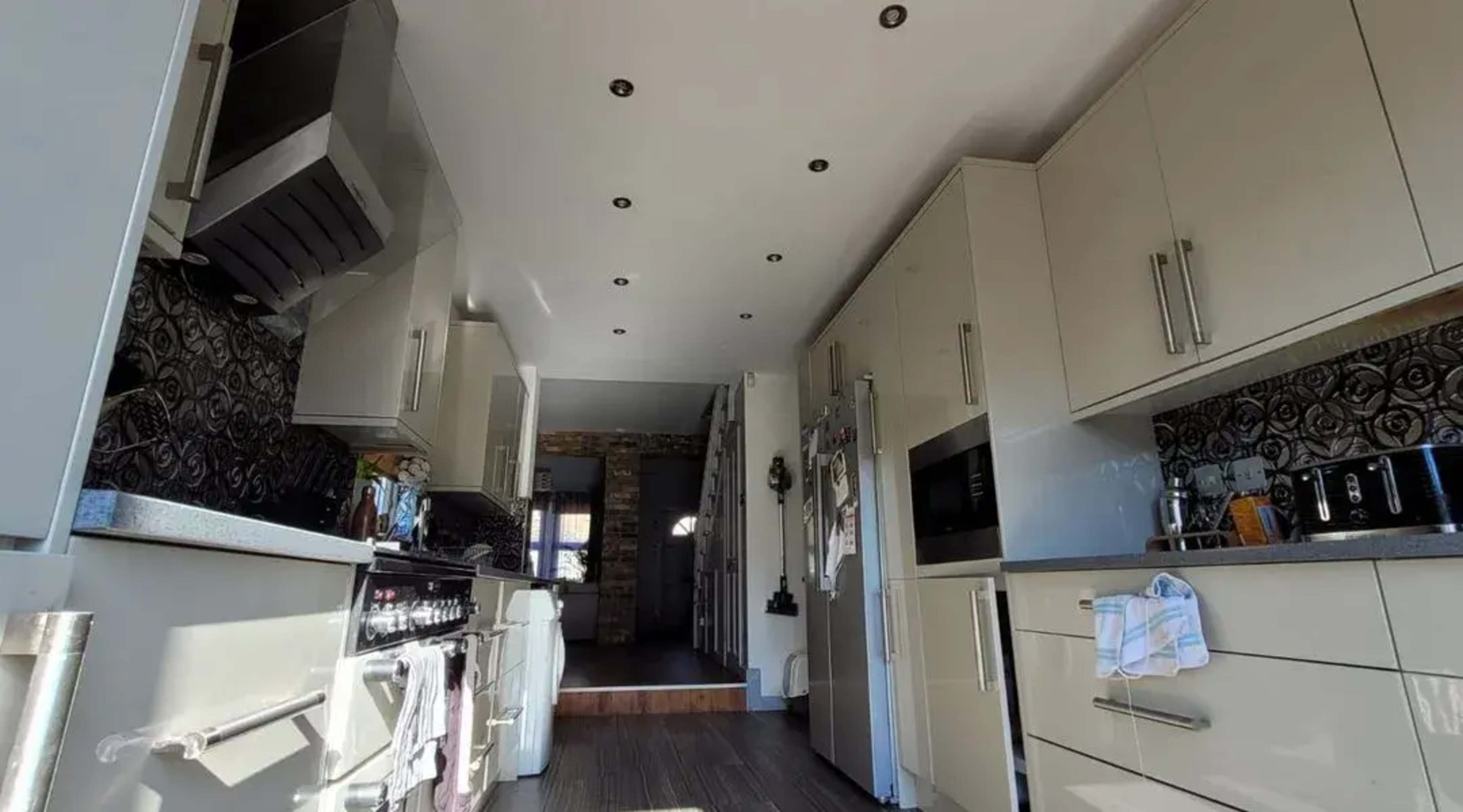 A modern kitchen with light-colored cabinets, stainless steel appliances, and a patterned backsplash.