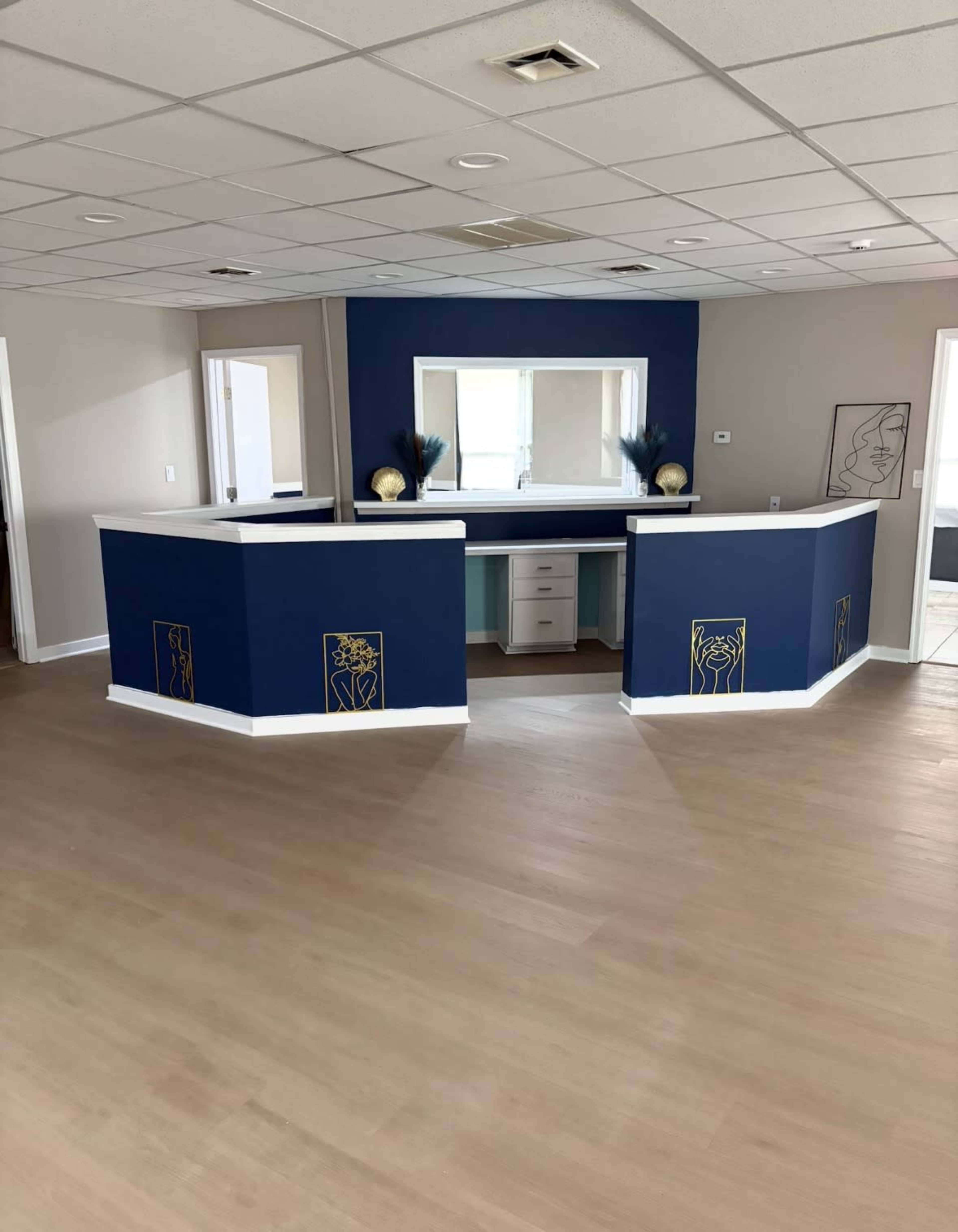 The image shows a modern reception area with blue accent walls, two curved desks, and minimal decor.