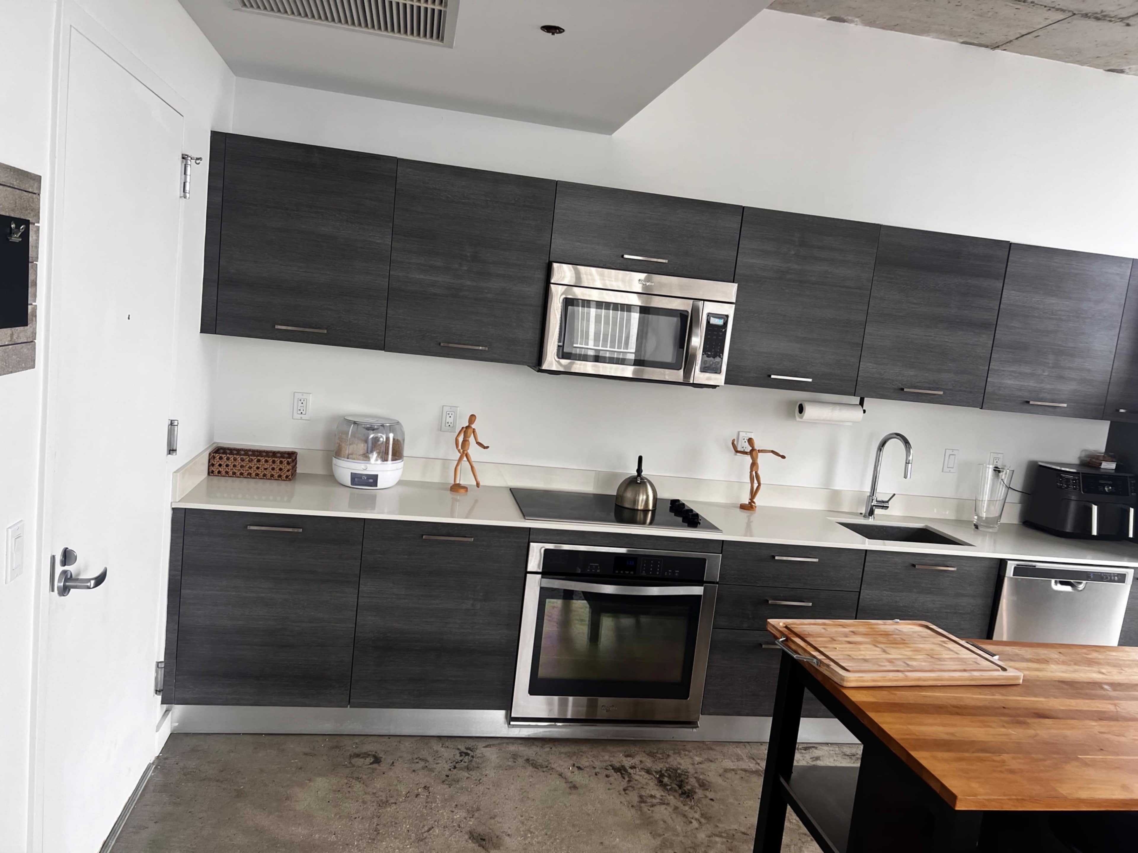 The image shows a modern kitchen with gray cabinetry, stainless steel appliances, and a wooden countertop island.