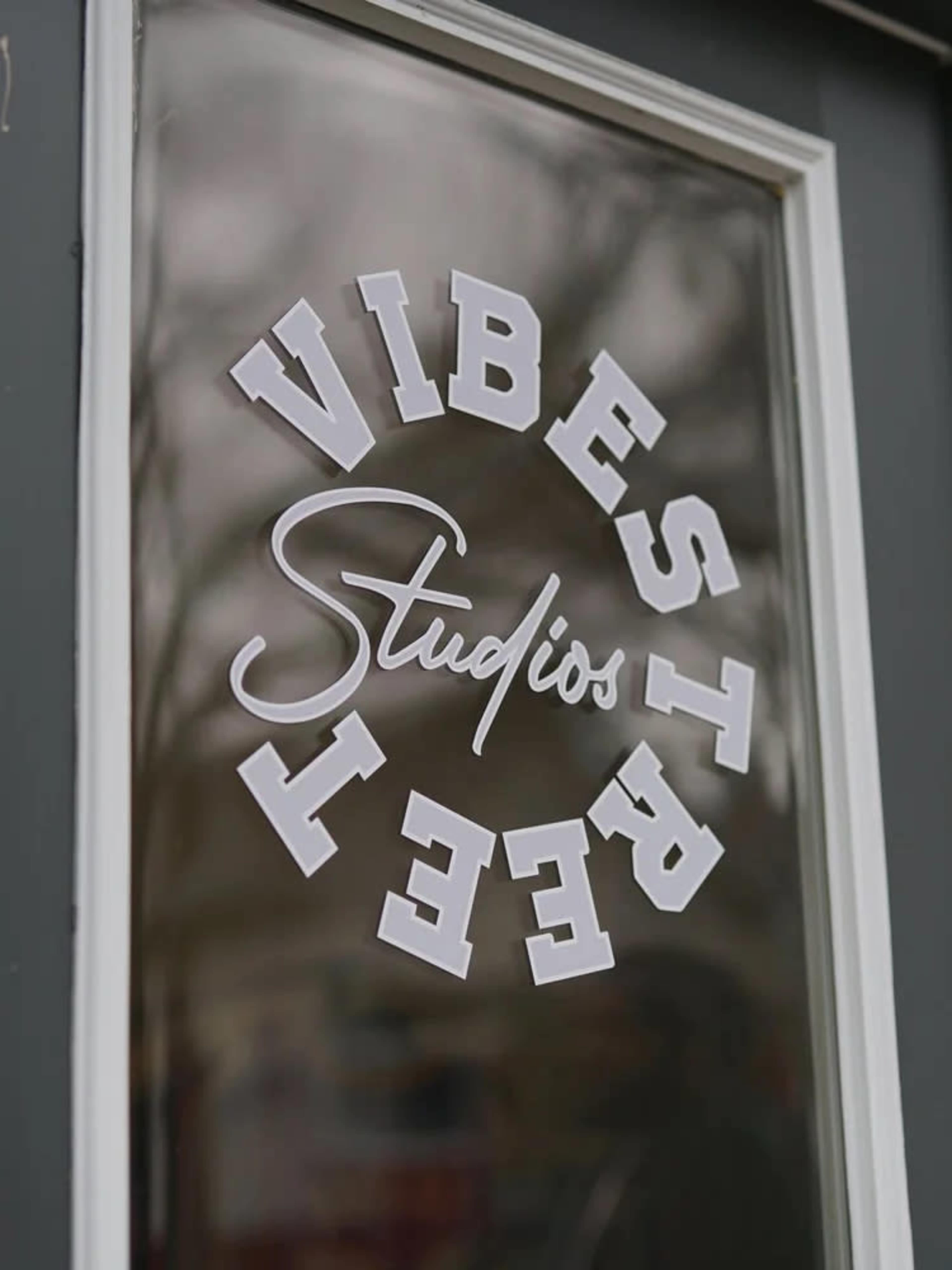 A storefront window displays a sign that reads "Vibes Studios" in a circular design.