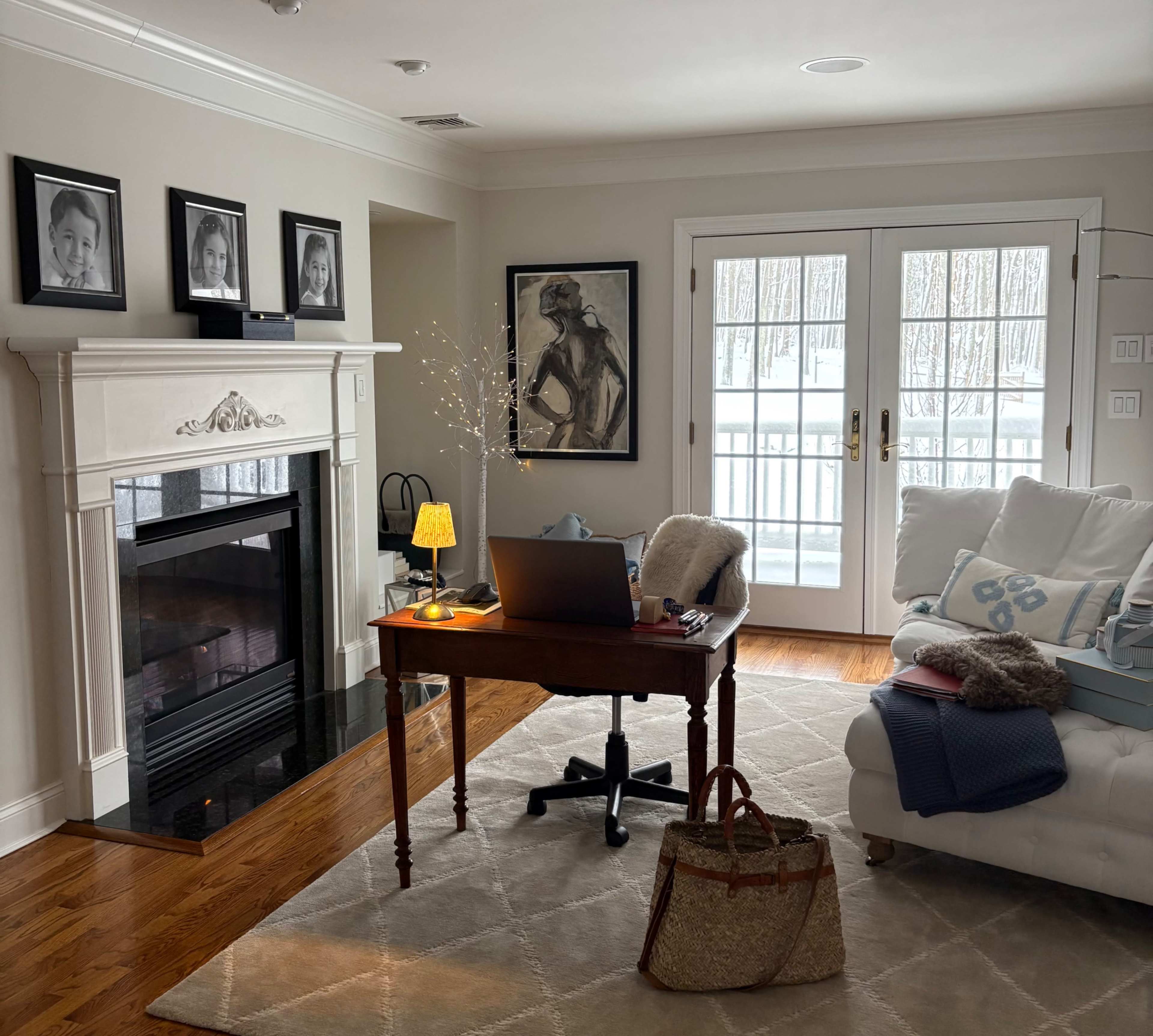 The scene features a living room with a desk, a sofa, a fireplace, and large windows showing a snowy outdoor landscape.