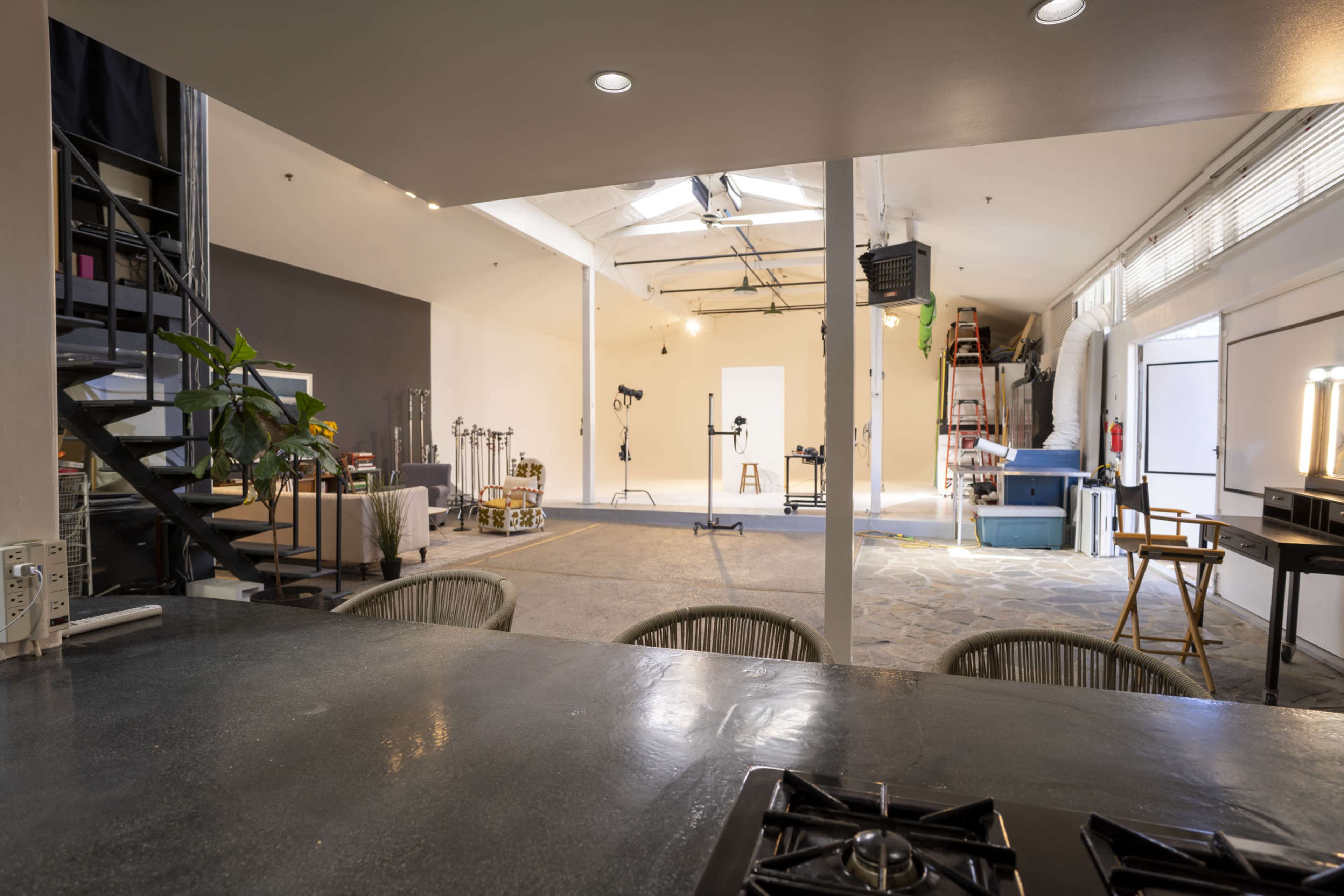 A spacious studio with a seating area, a spiral staircase, and various equipment arranged for photo or video production.