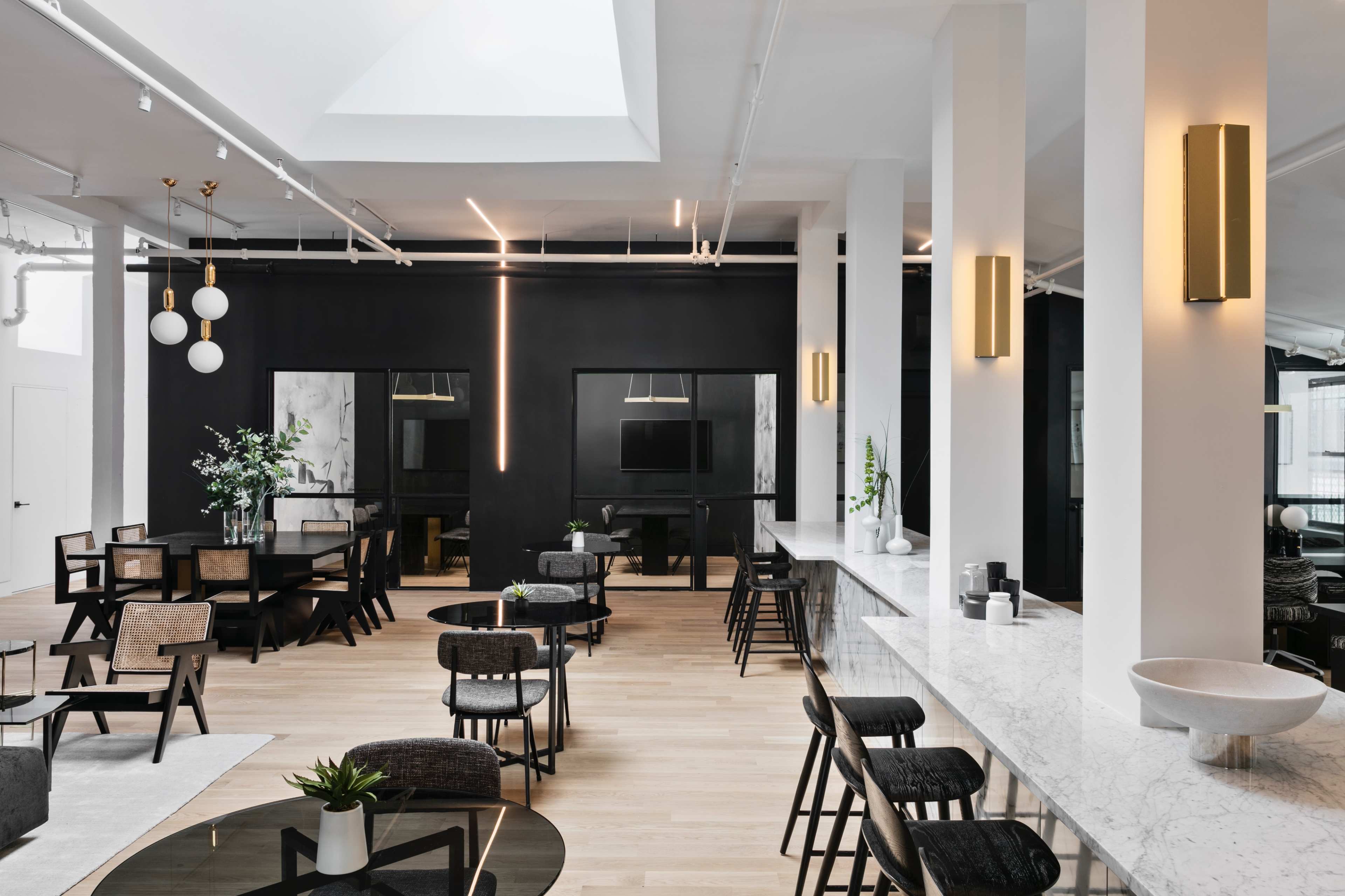 A sleek, contemporary interior features a mix of dining and seating areas with dark accents, marble surfaces, and ample natural light.