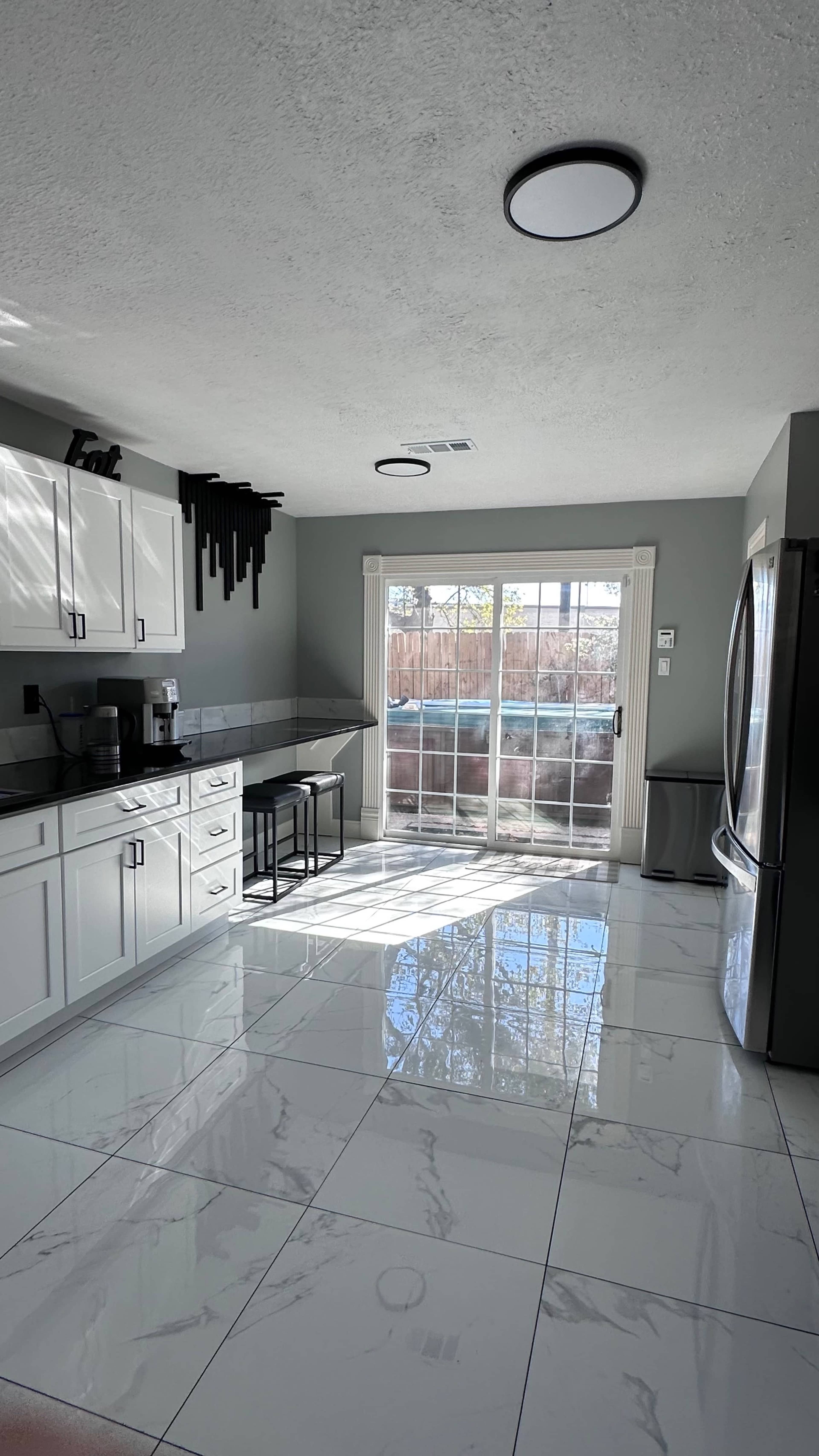 The kitchen features white cabinets, a gray countertop, and a large sliding glass door leading to an outdoor area.