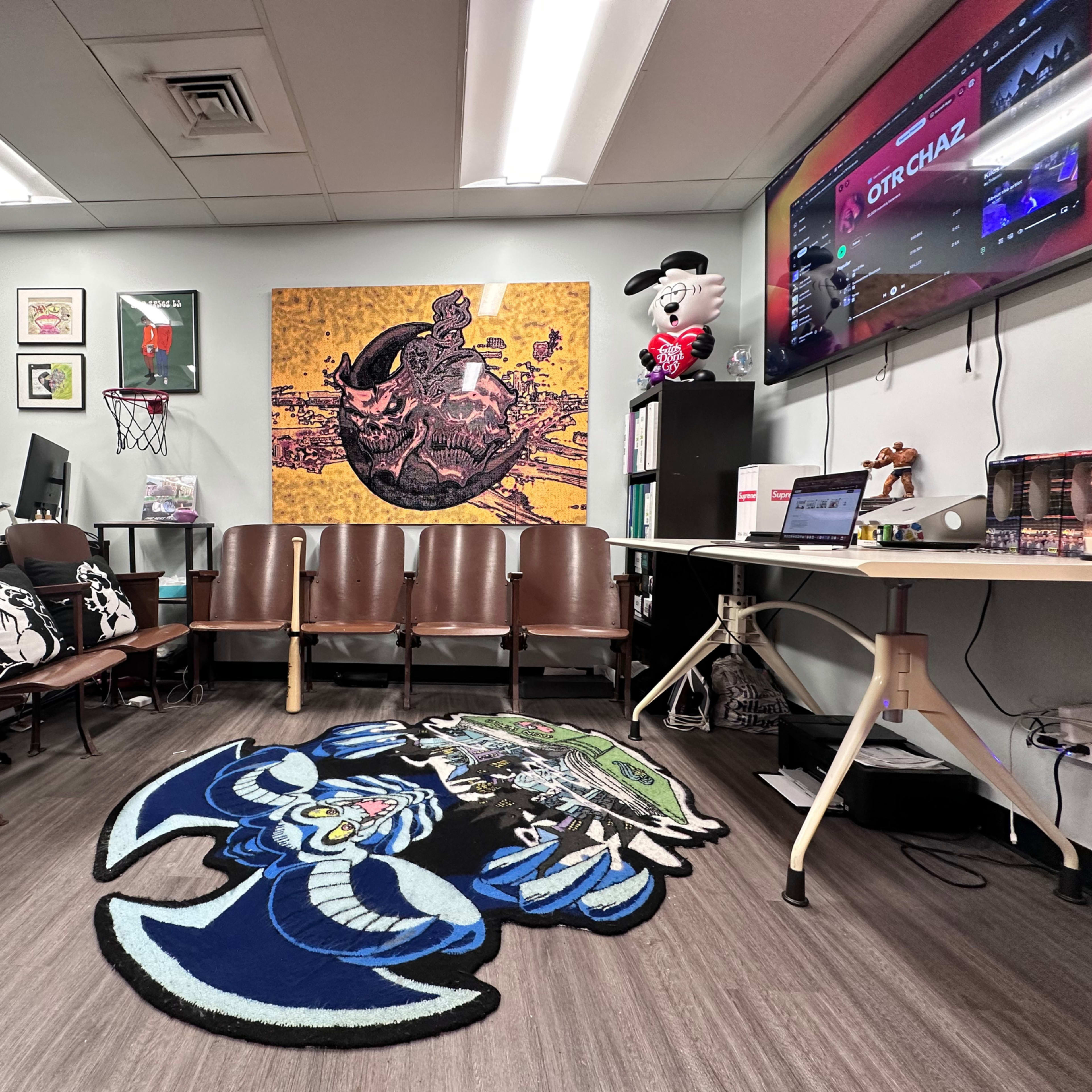 The image shows a waiting room with brown chairs, a large decorative wall art piece, a television displaying sports content, and a blue cartoon-themed rug on the floor.