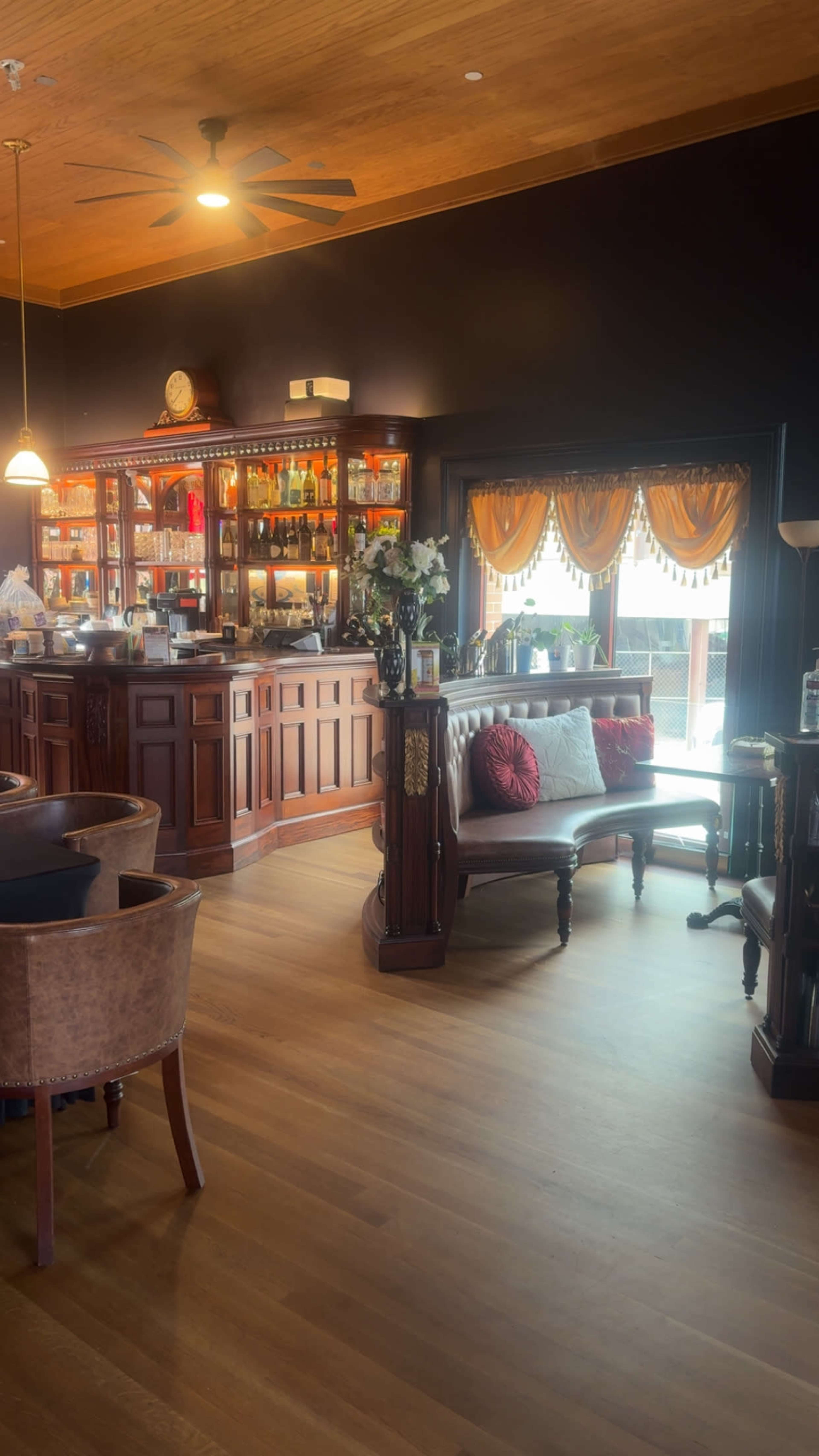 The image shows a stylish bar area with wooden furnishings, a well-stocked back bar, and cozy seating arrangements.