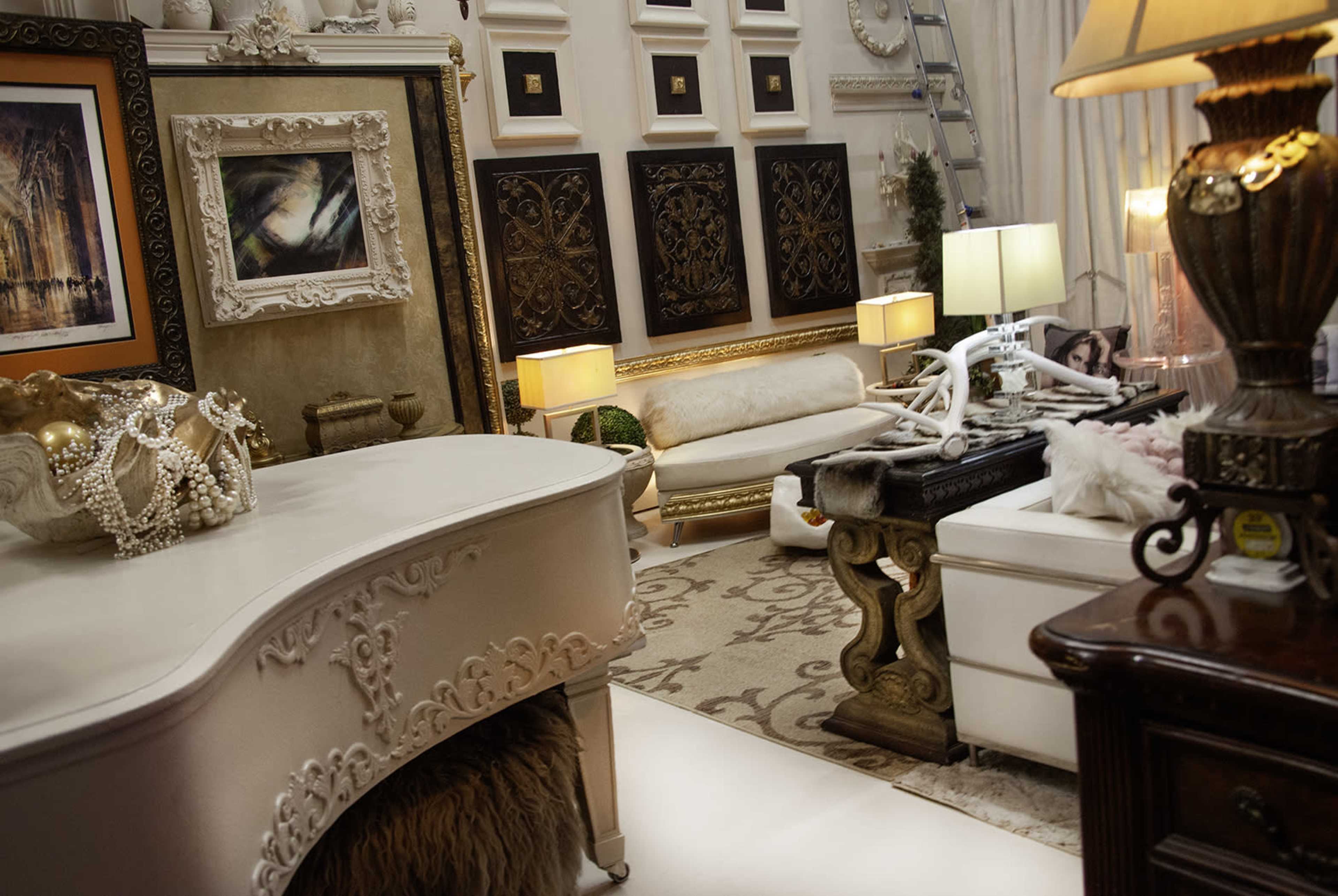 The image features a stylish interior room showcasing ornate decor, including framed artworks, elegant furniture, and decorative elements like lamps and sculptures.