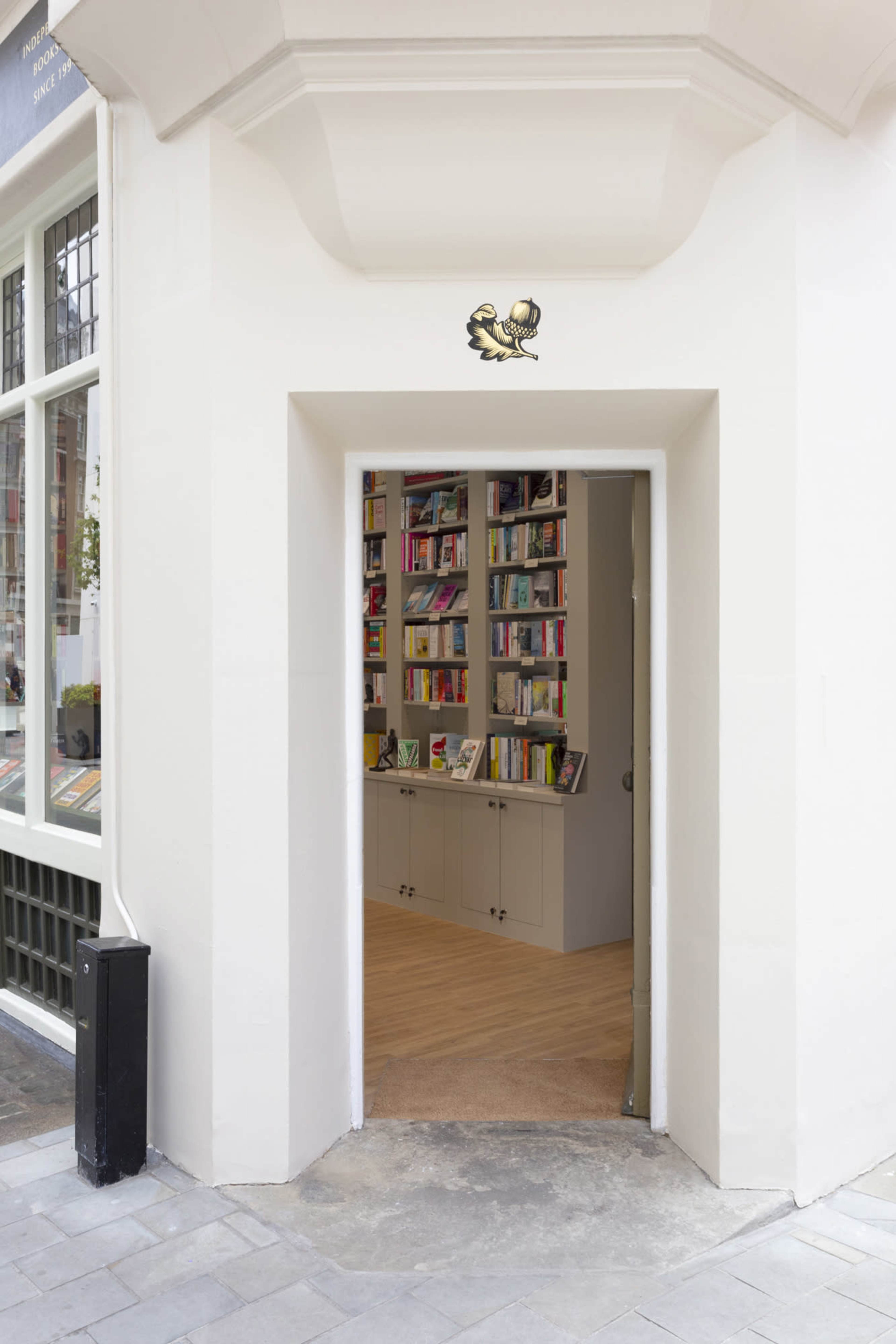 A doorway leads into a well-organized bookstore featuring shelves filled with books.