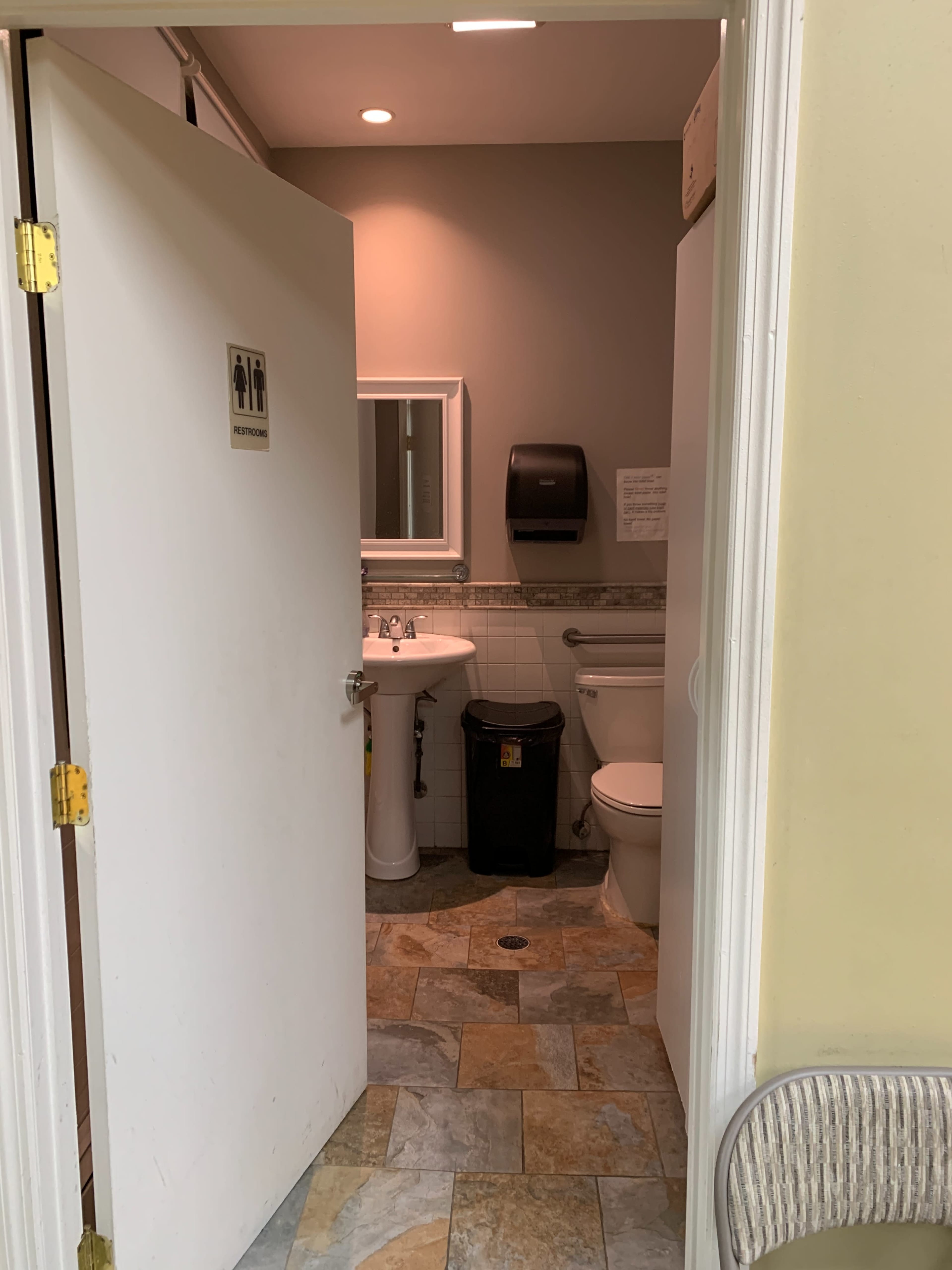 The image shows the entrance to a bathroom with a sink, toilet, and a hand dryer visible inside.