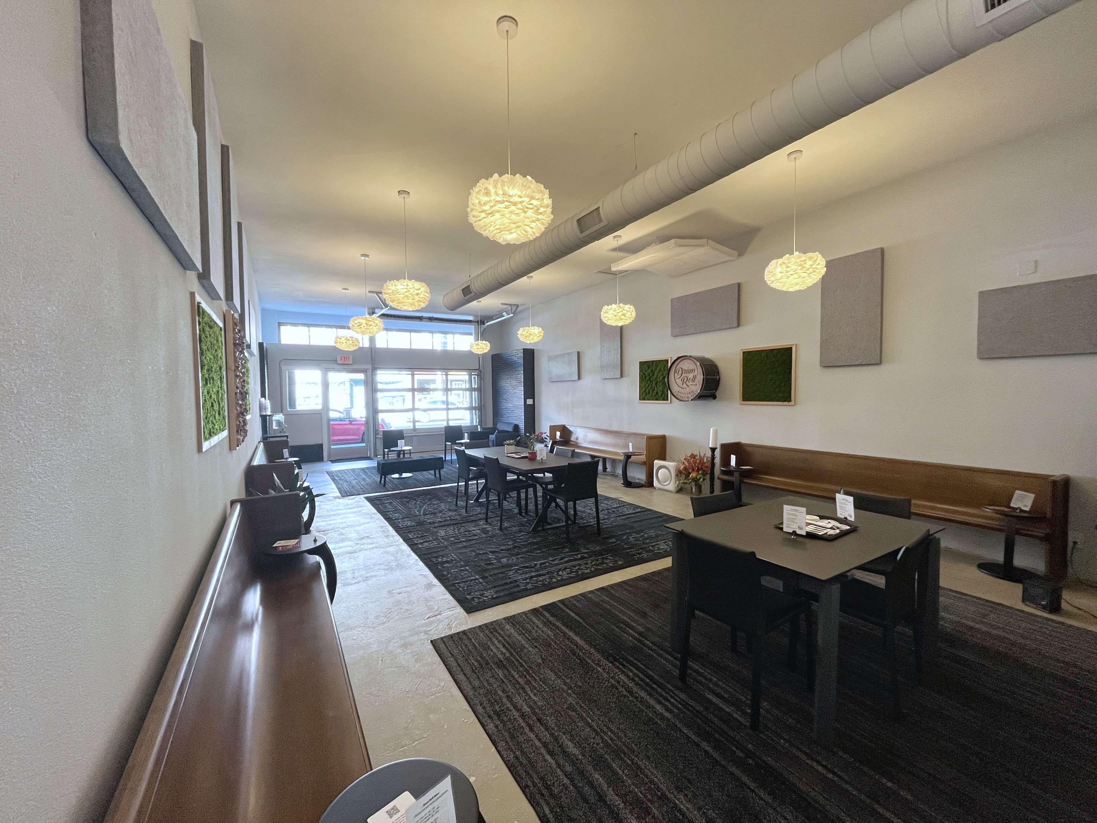 A modern interior of a café with wooden benches, tables, decorative wall panels, and hanging light fixtures.
