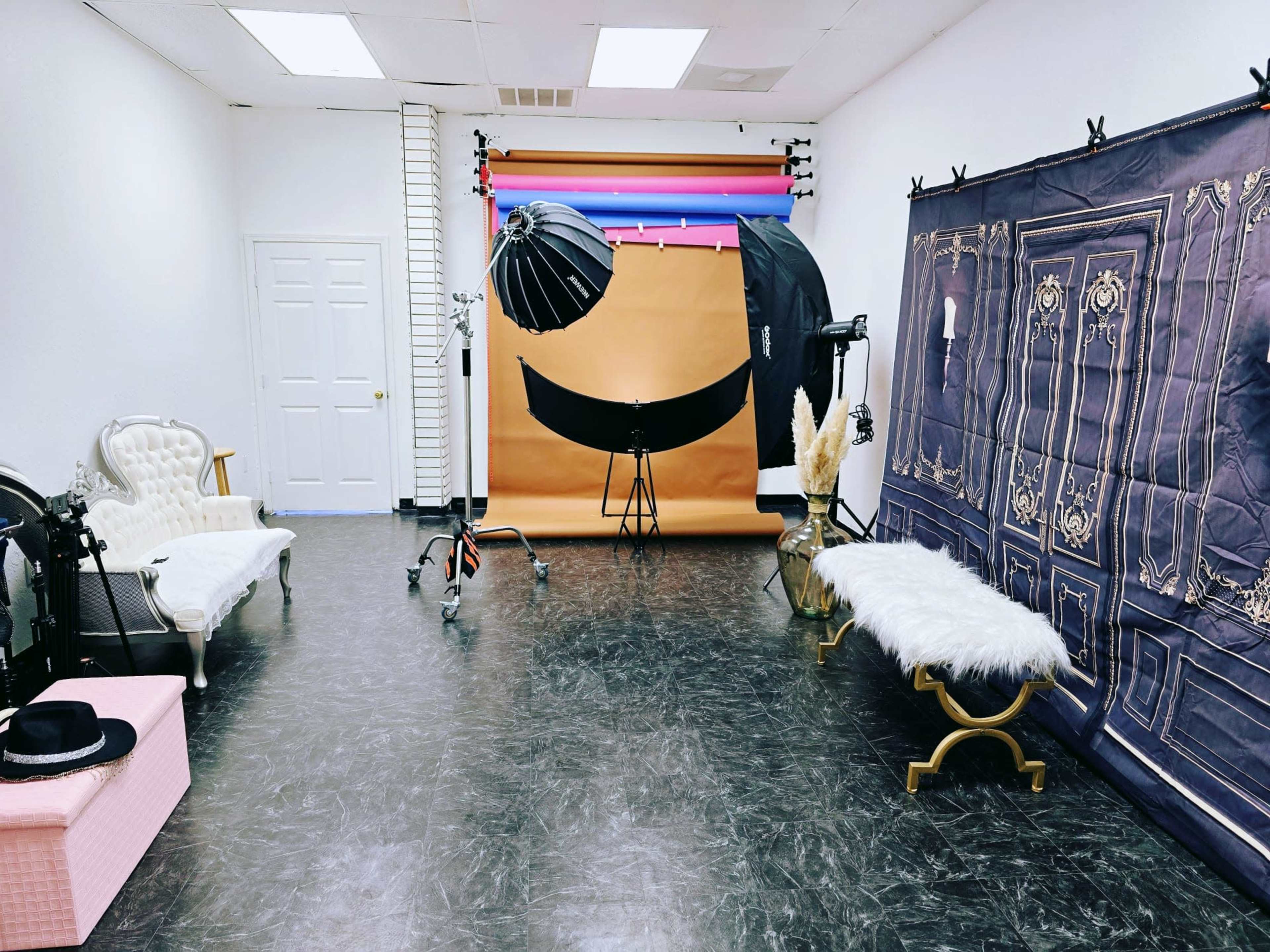A photography studio featuring a backdrop, lighting equipment, and various benches arranged in the space.