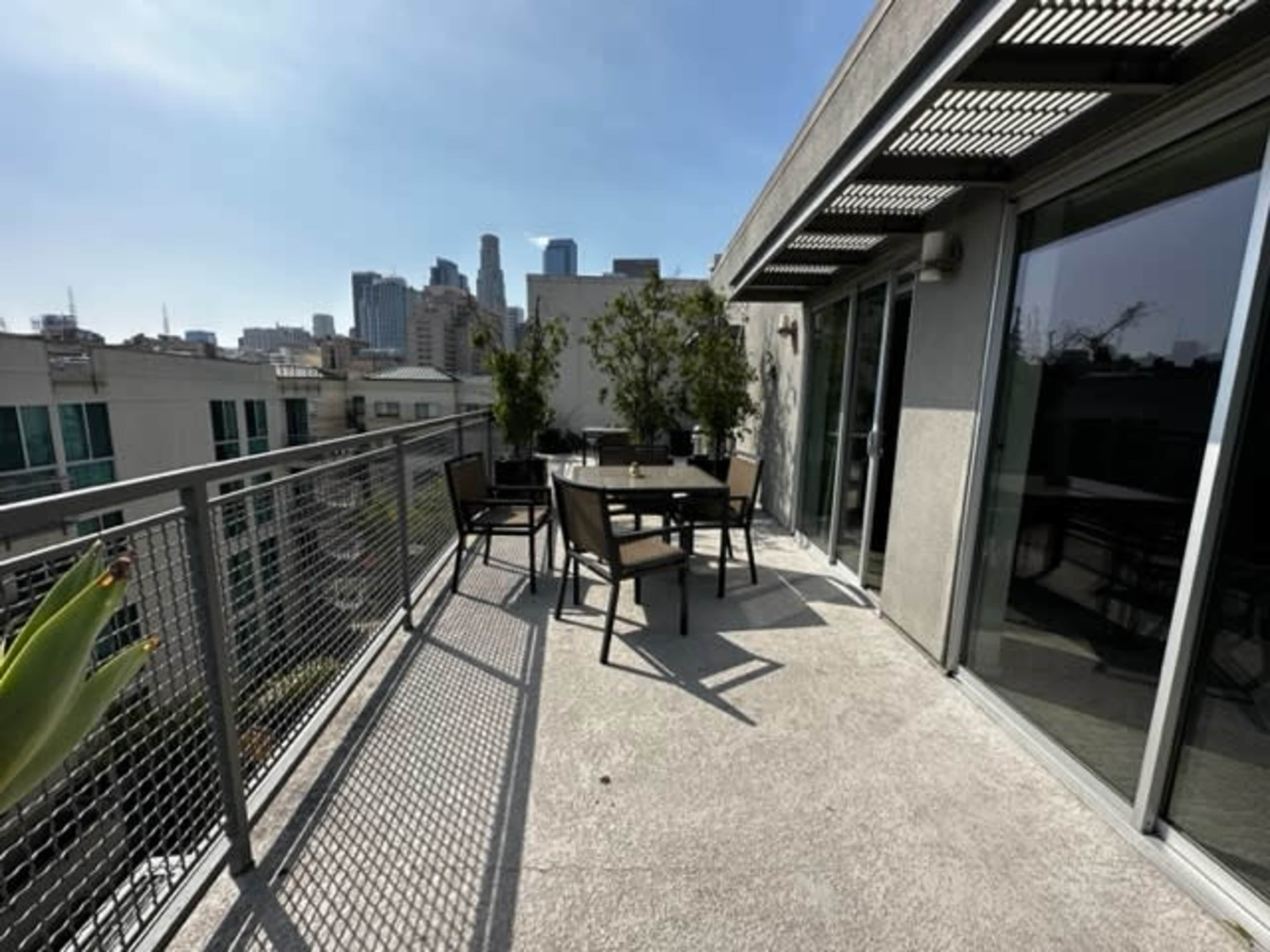 A rooftop terrace with outdoor seating and a view of city skyscrapers in the background.