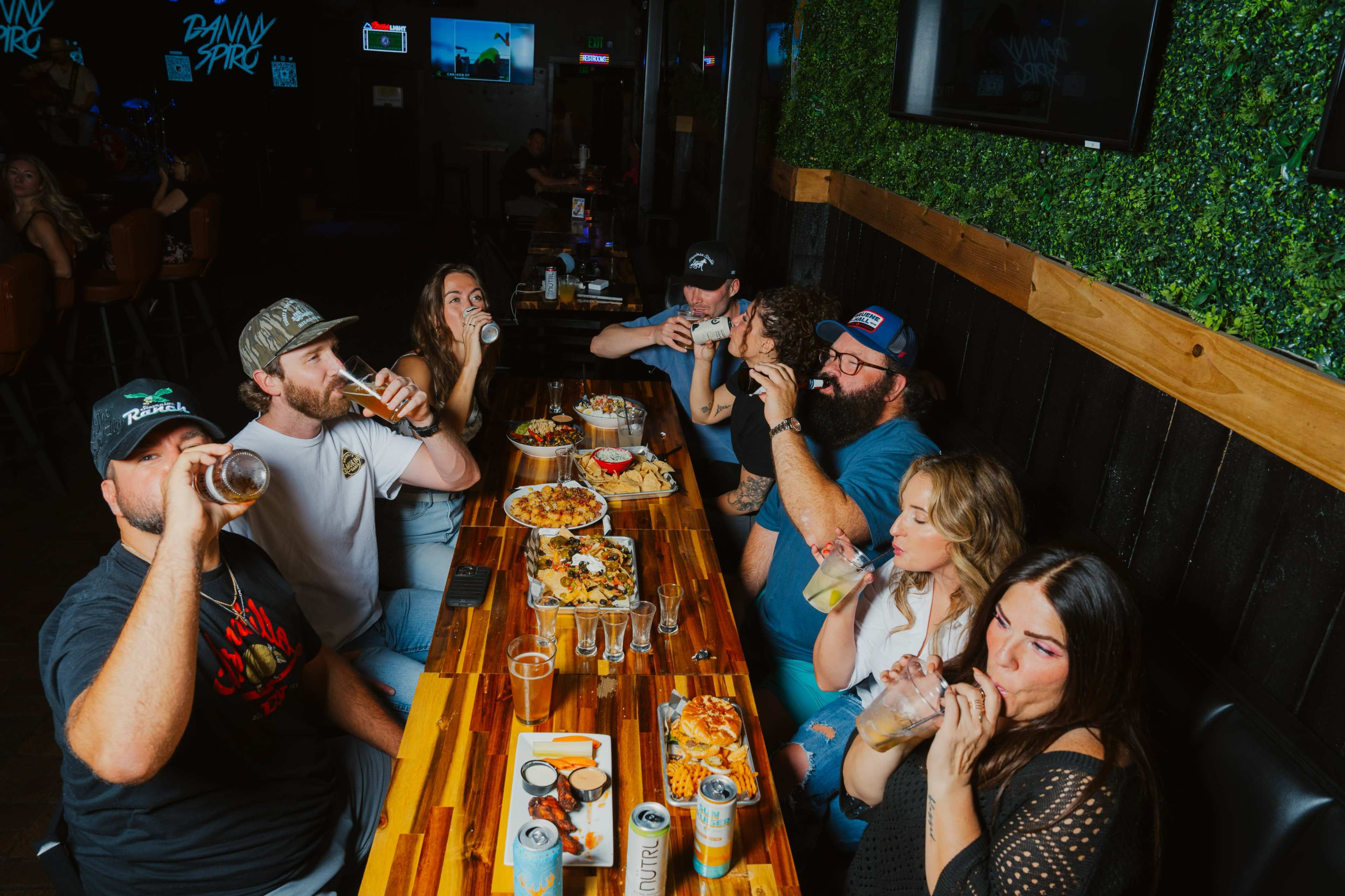 A group of people sits around a table at a restaurant, enjoying food and drinks together.
