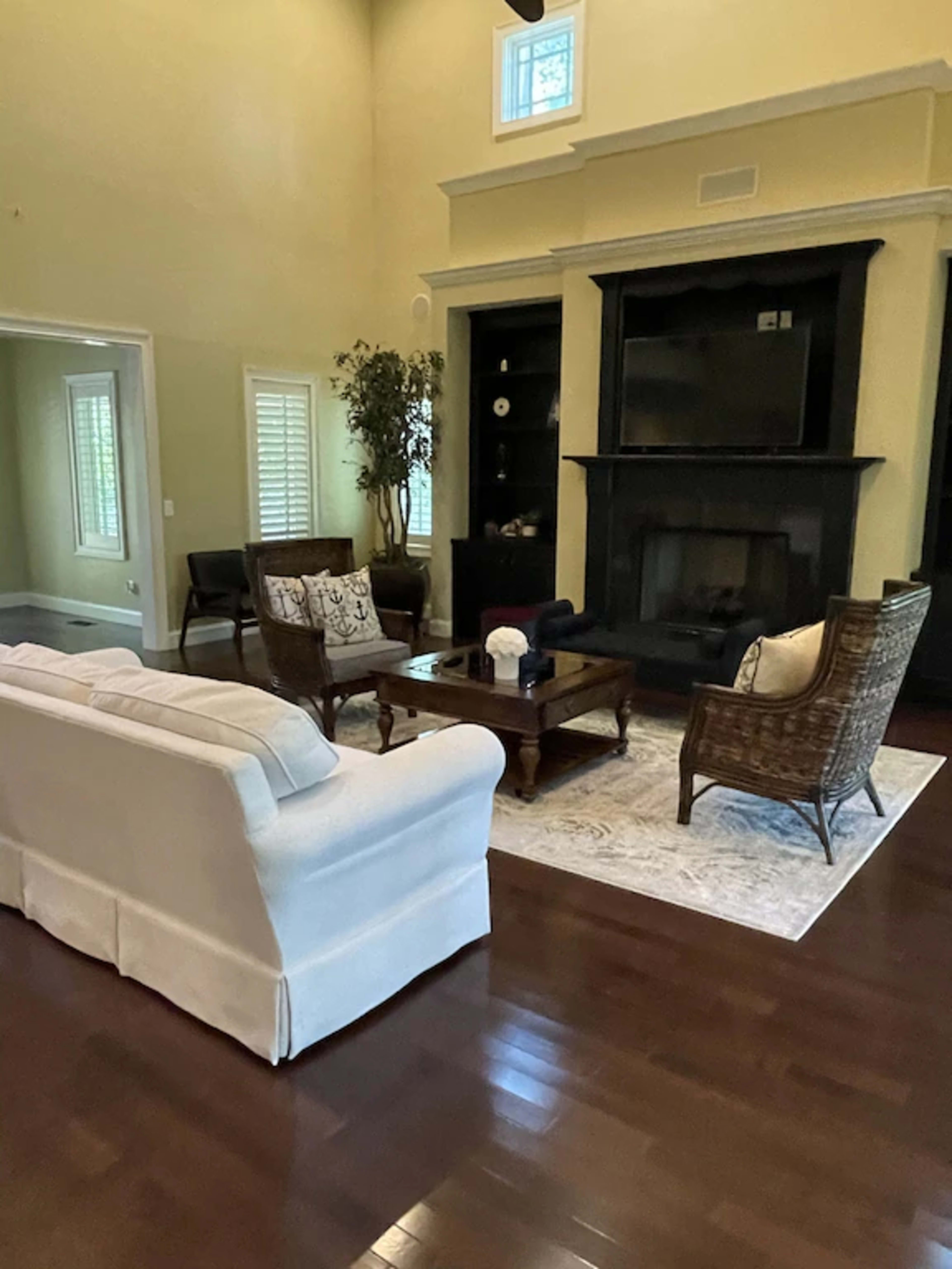 A spacious living room with a light-colored sofa, dark wooden furniture, and a fireplace.
