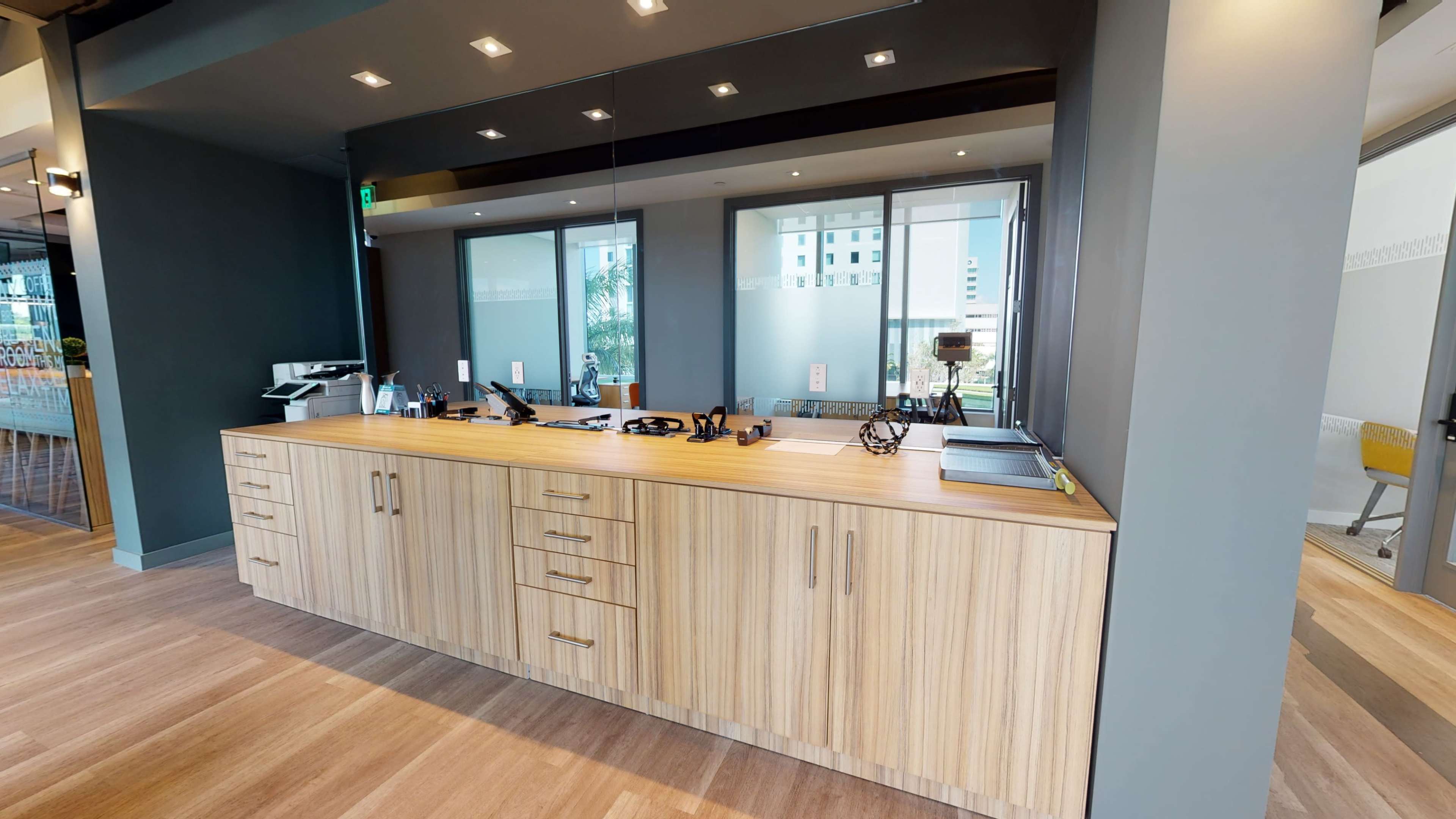 A modern reception area with a wooden counter featuring multiple drawers and a mirror behind it.