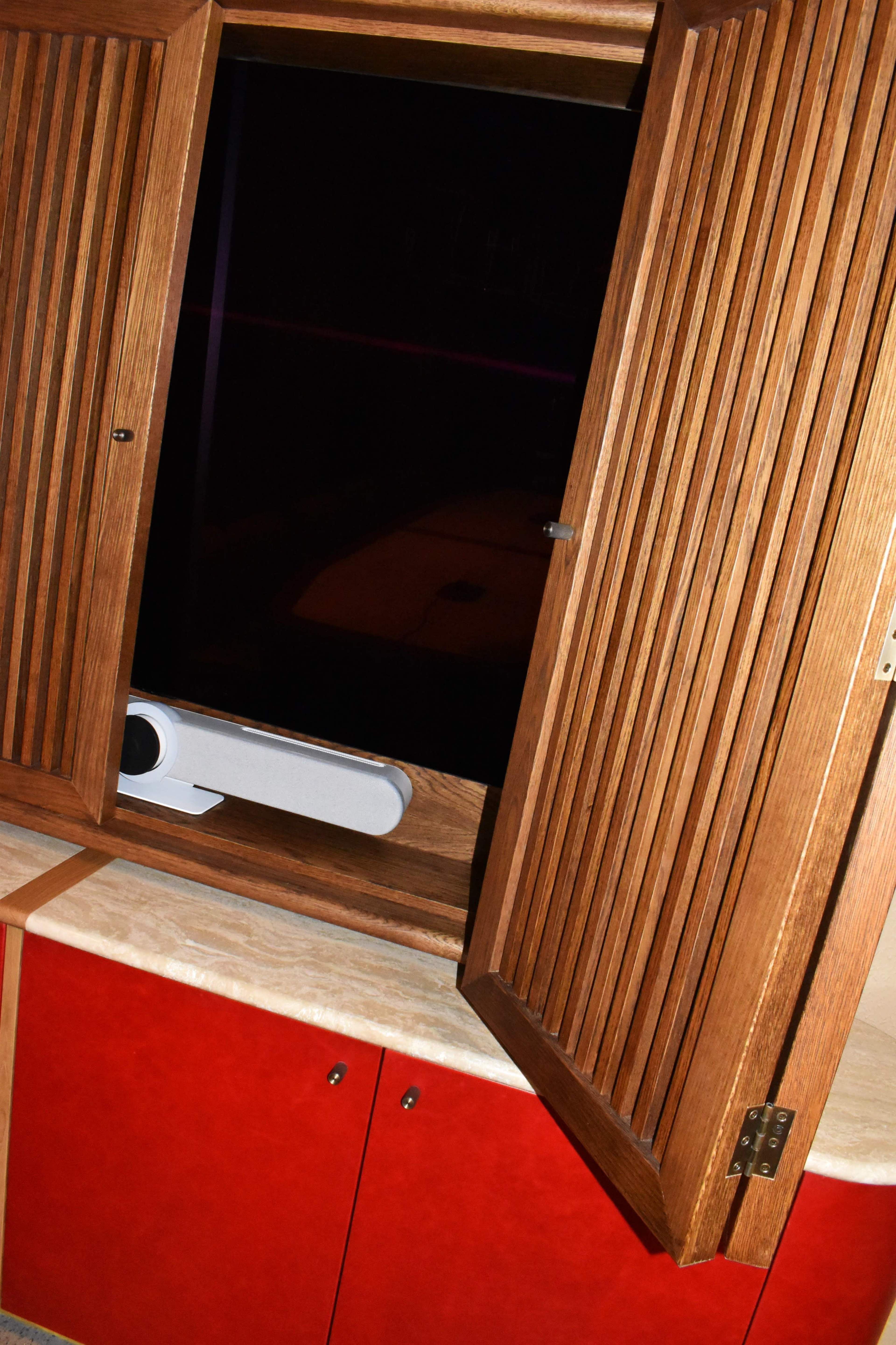 The image shows a wooden window with slats opened above a countertop featuring red cabinetry.