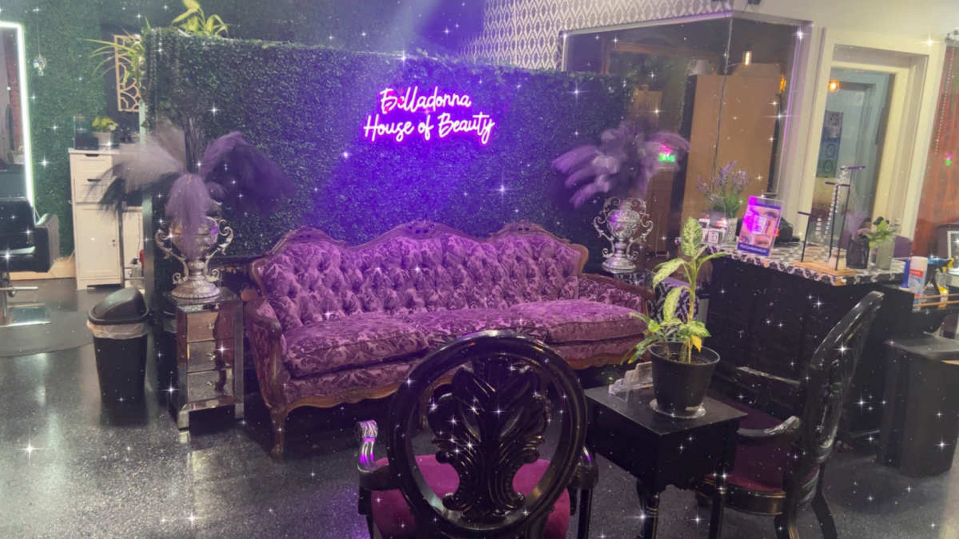 The image shows a beauty salon interior with a purple velvet couch, decorative plants, and a neon sign reading "Feliciana House of Beauty."