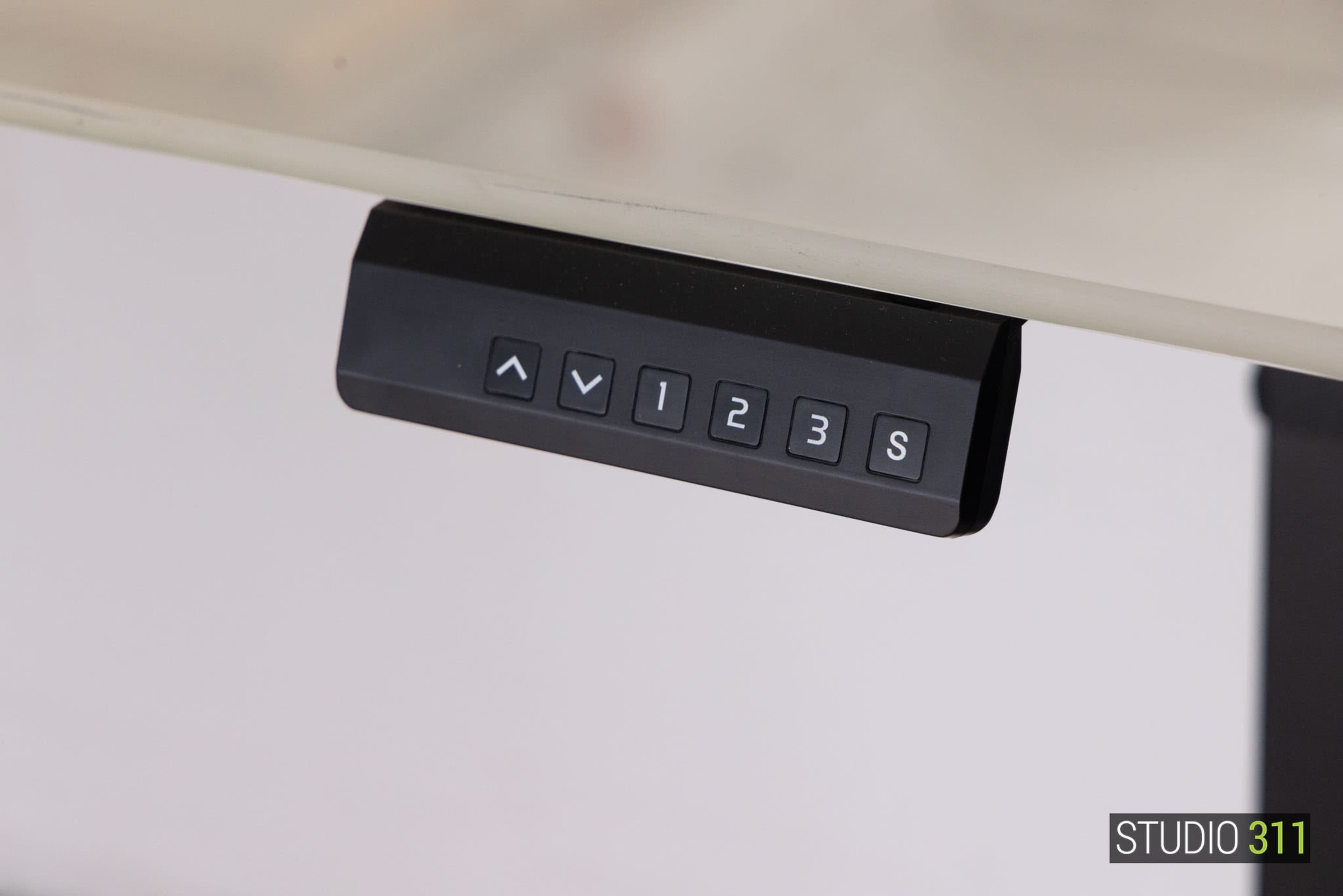 The image shows a black control panel with buttons labeled with arrows and numbers on a glass surface.