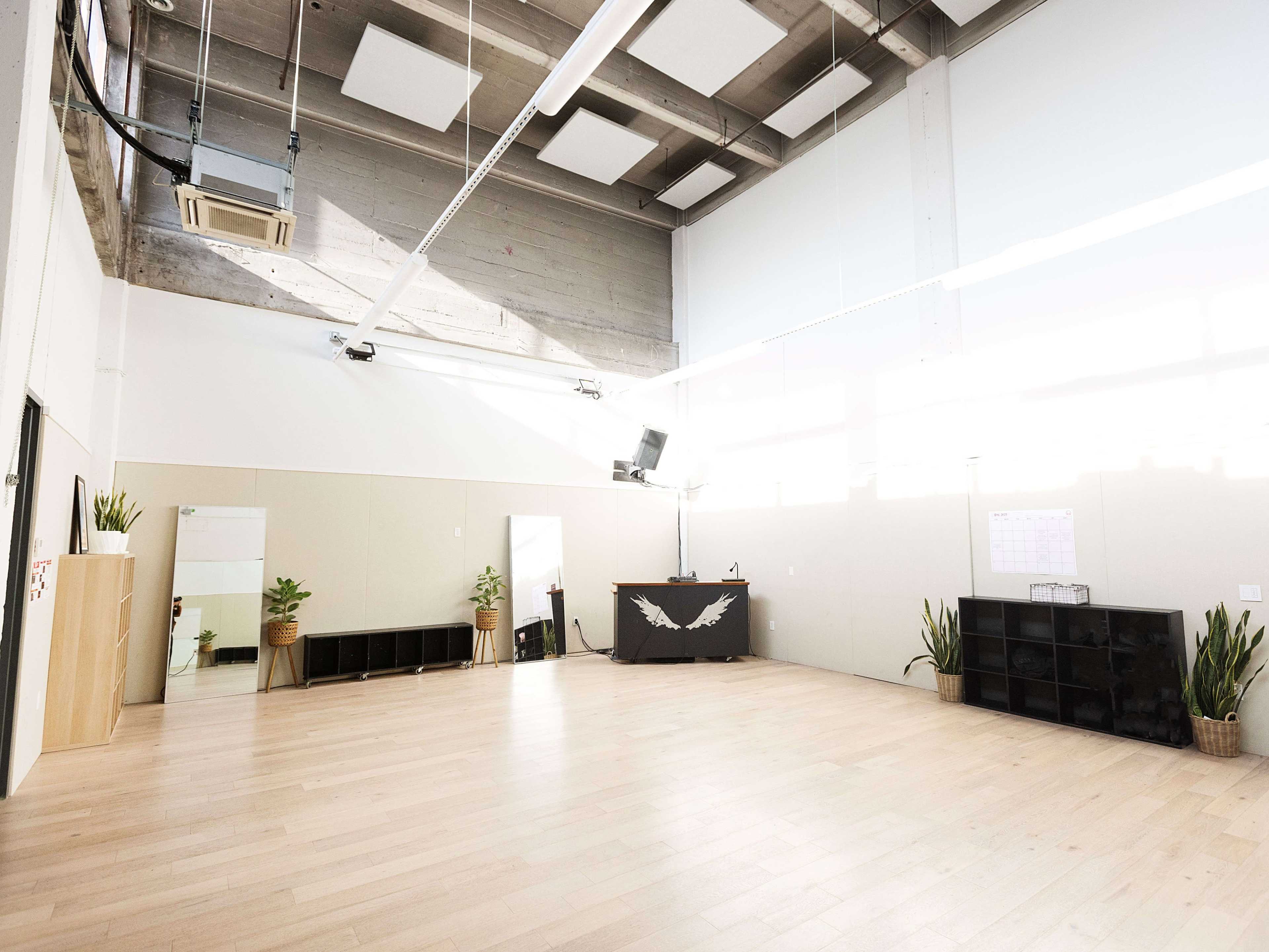 A spacious, well-lit room with wooden flooring, a reception area at the front, and shelving units along the walls.