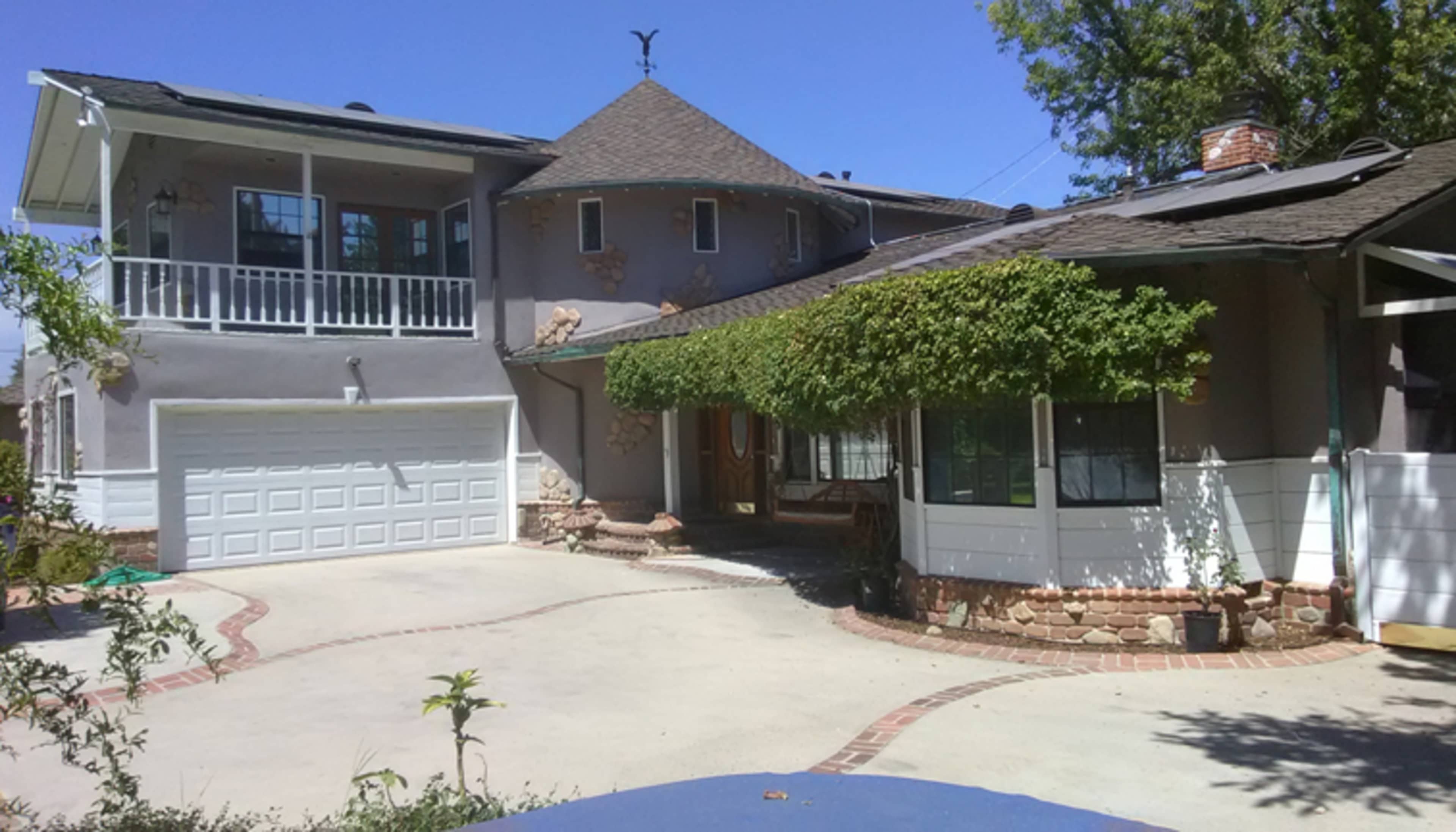 A unique house with a round turret, a two-car garage, and a driveway lined with brick patterns.