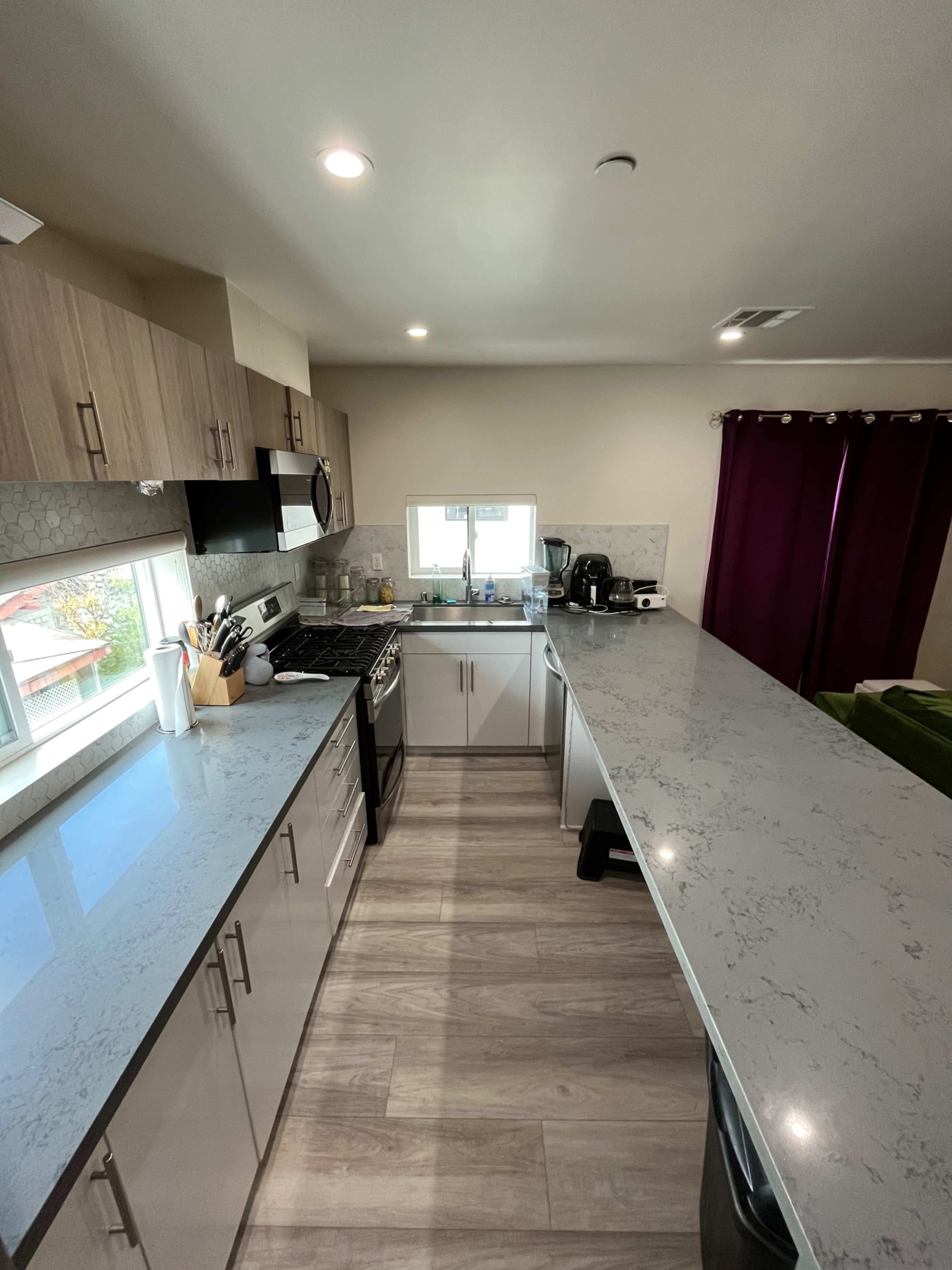The kitchen features modern cabinetry, a sleek countertop, and a large window providing natural light.