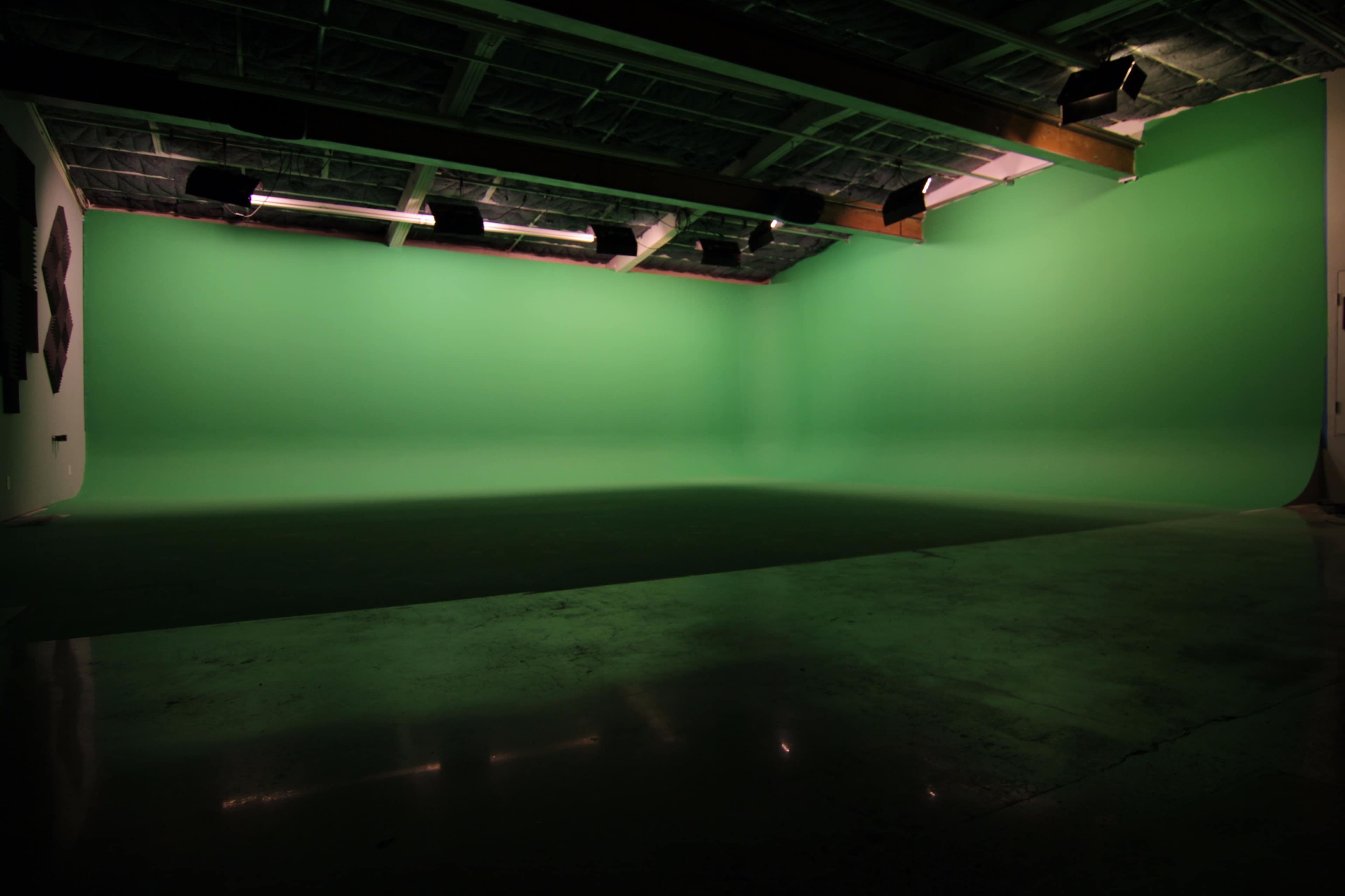 A large studio space with a bright green backdrop and a polished floor.