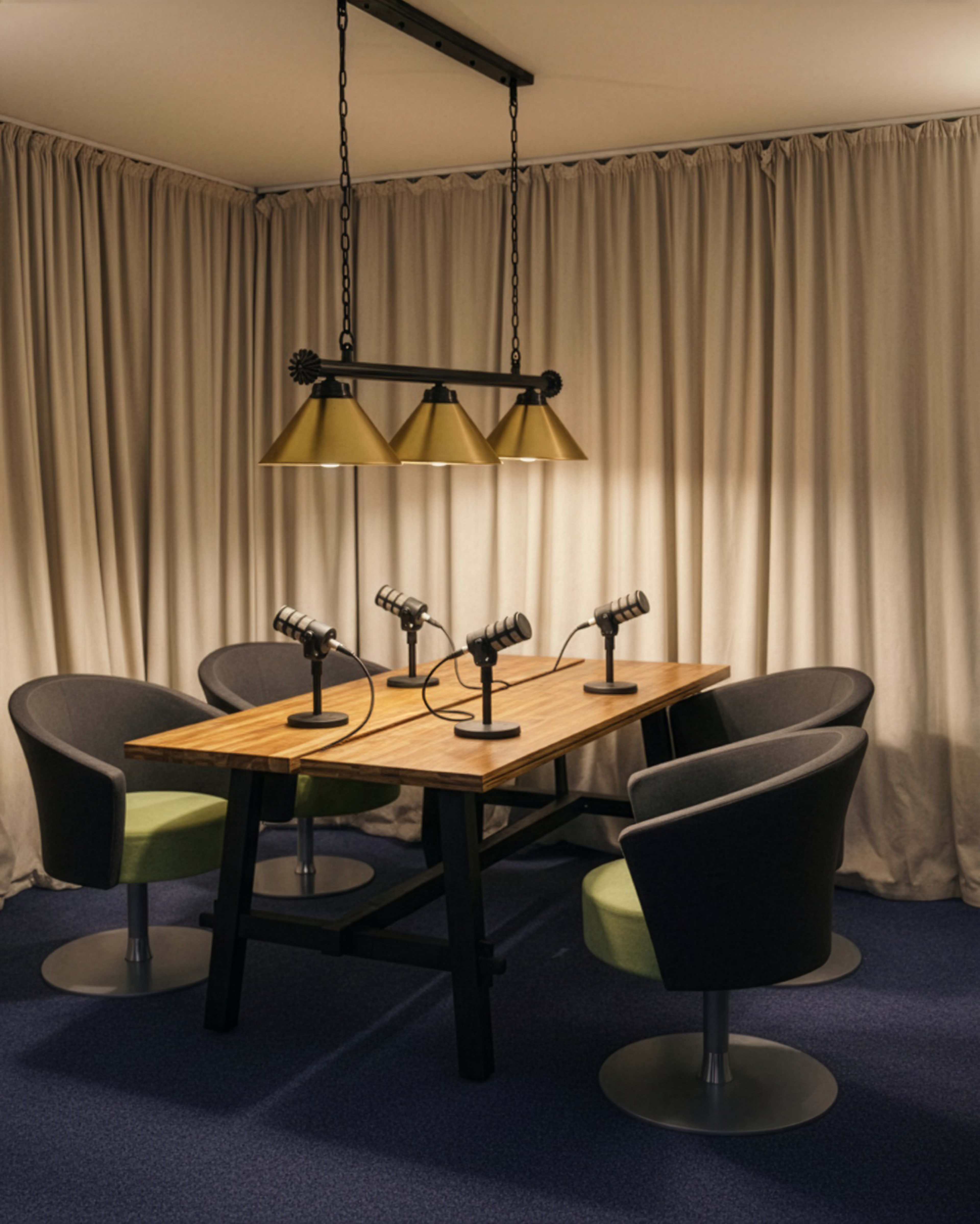 A modern meeting room features a wooden table surrounded by four ergonomic chairs and equipped with three desk lamps.