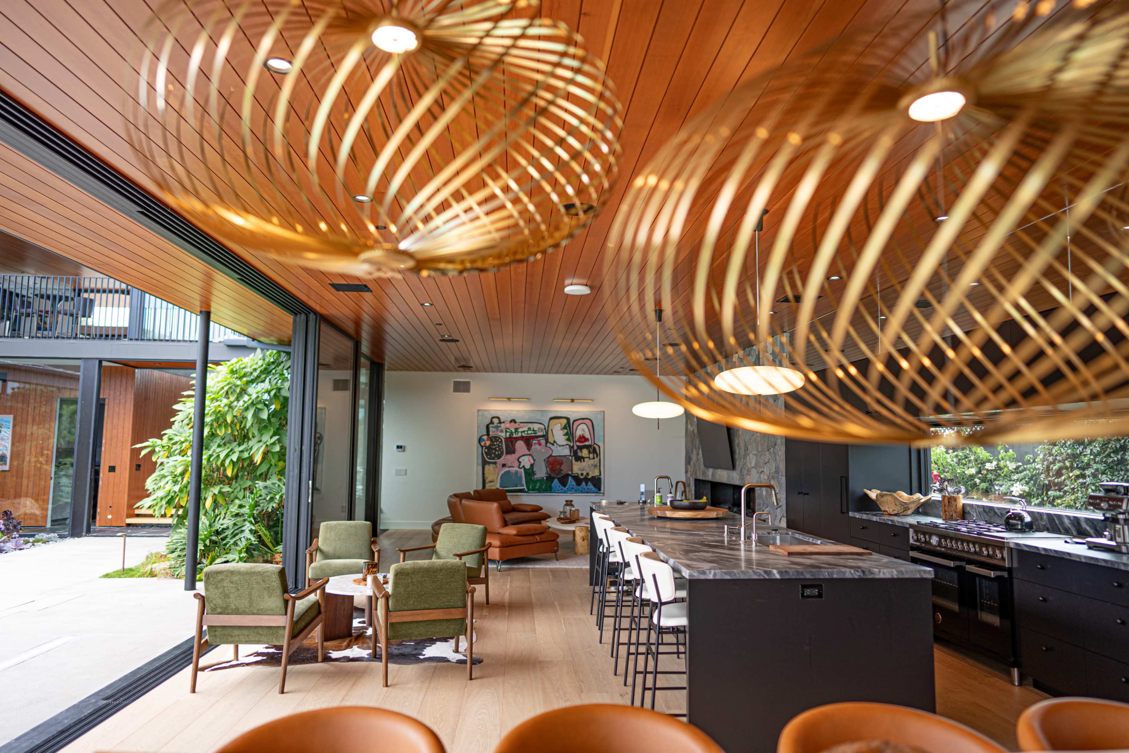 A modern kitchen and living area with wooden ceilings, large windows, and stylish seating arrangements.