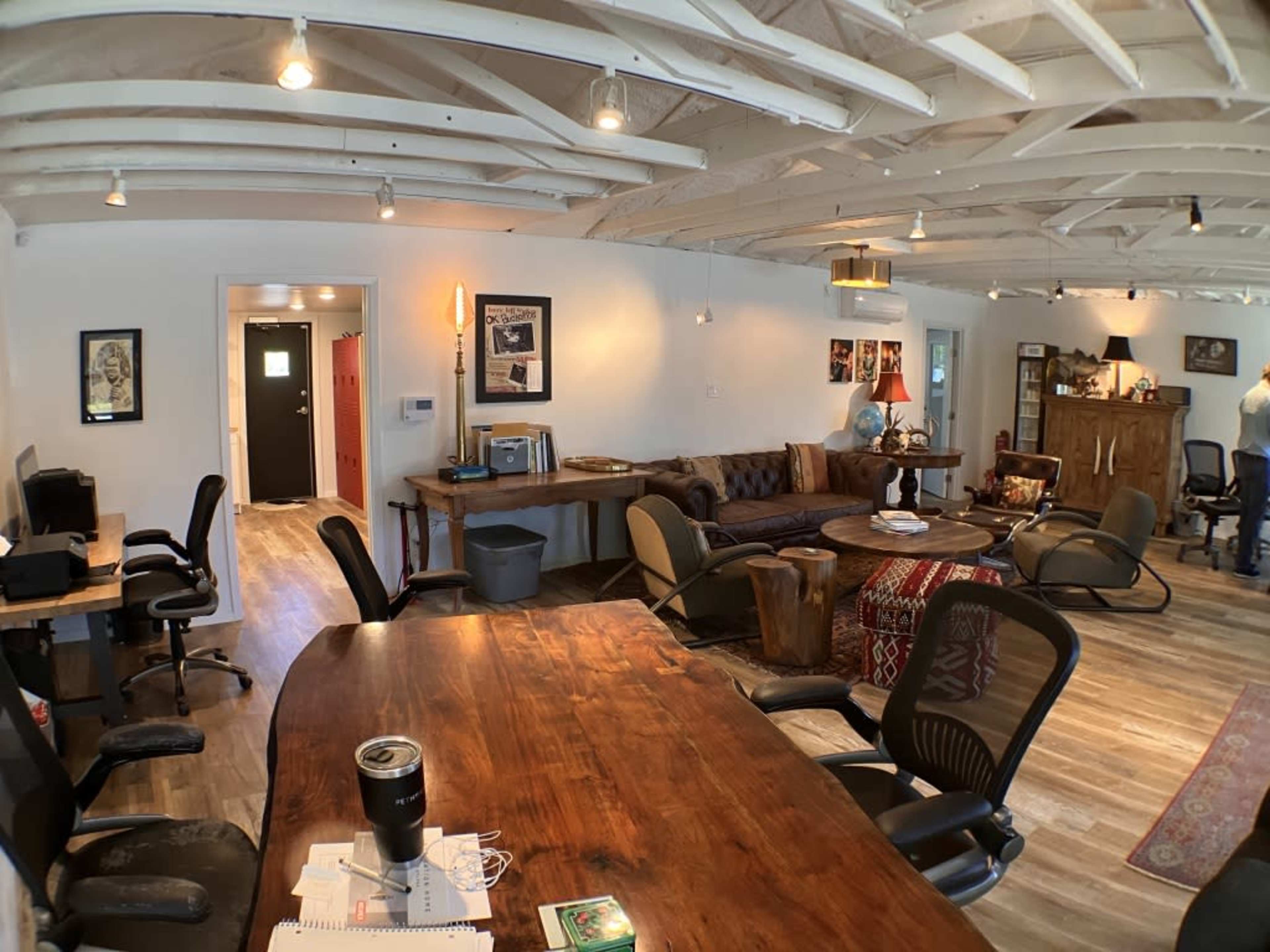 A spacious office with a wooden table, various seating areas, and a mix of modern and rustic decor.