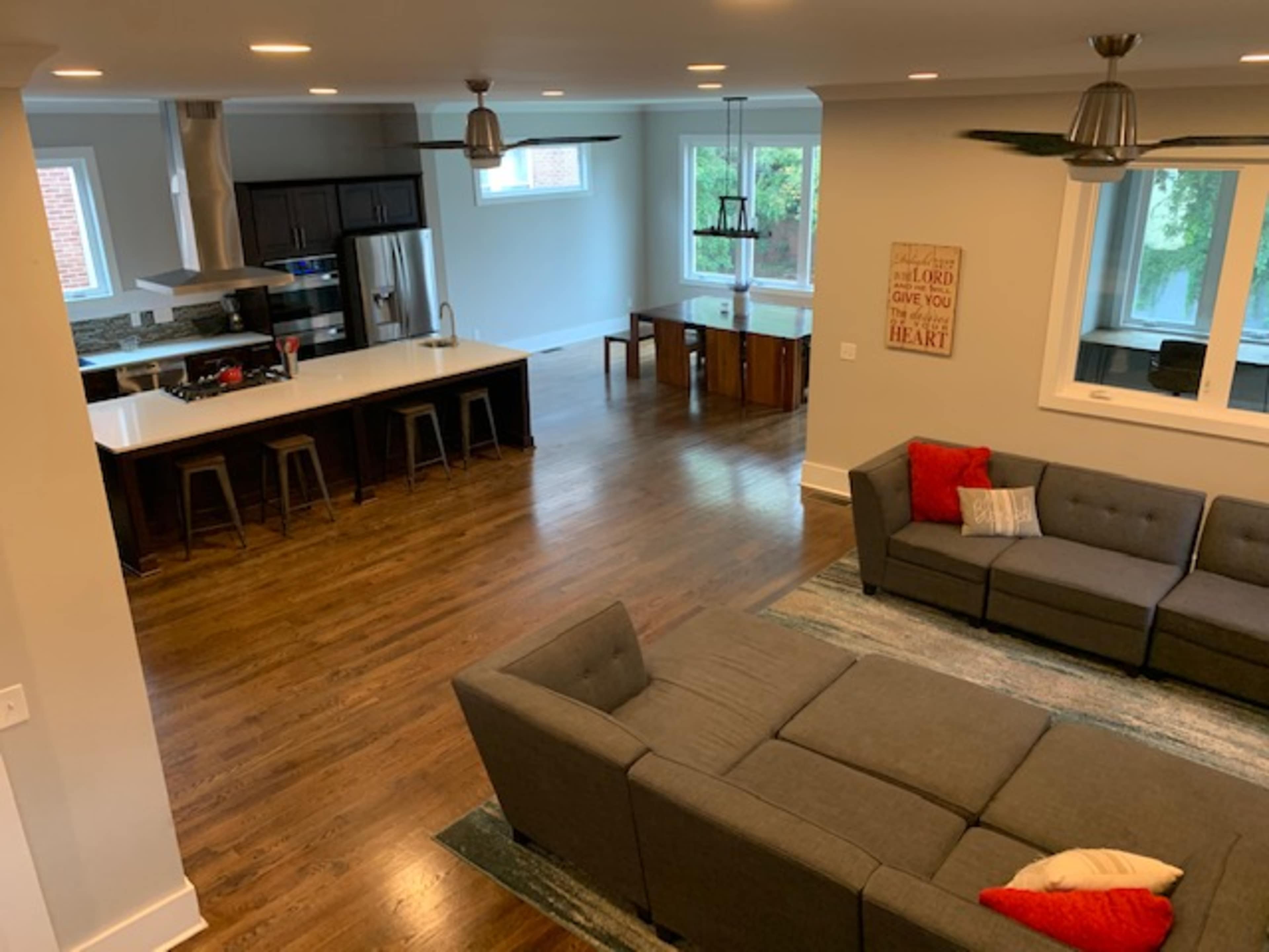 A spacious living area featuring a sectional sofa, a dining table, and a kitchen with modern appliances.