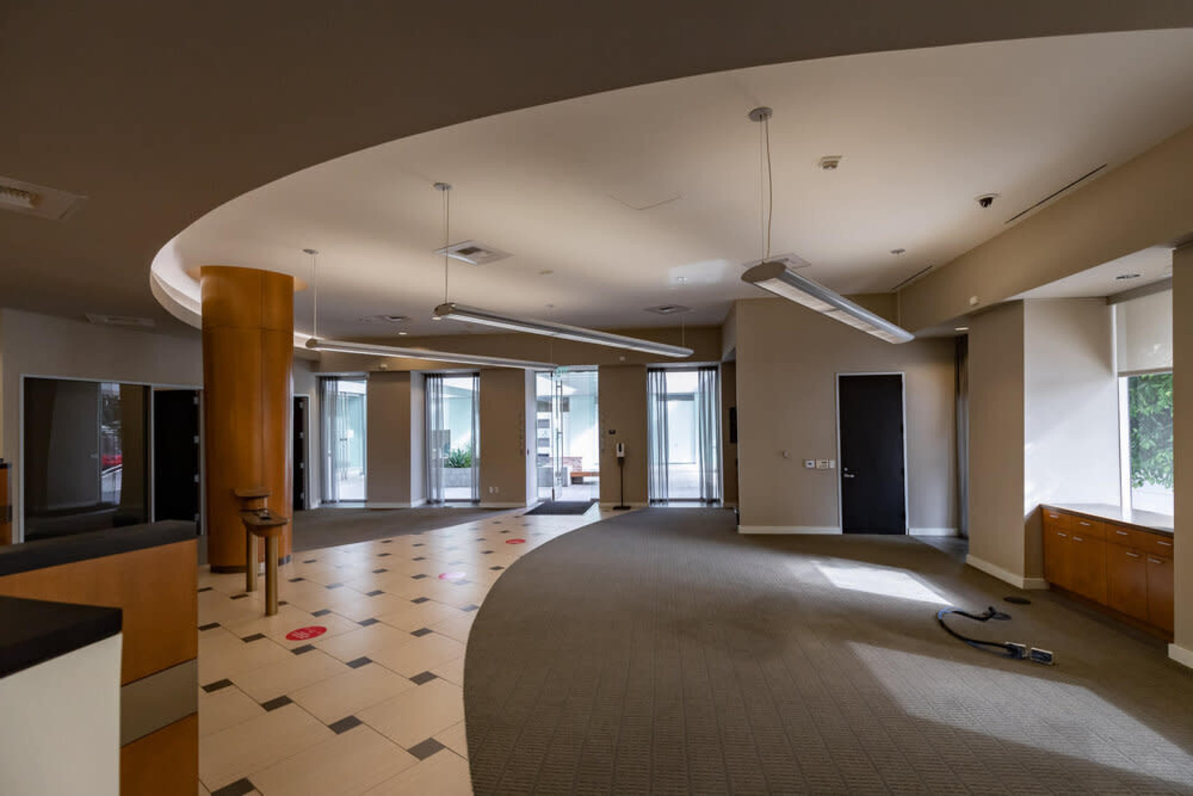 An empty office lobby featuring curved walls, recessed lighting, and a combination of carpet and tile flooring.