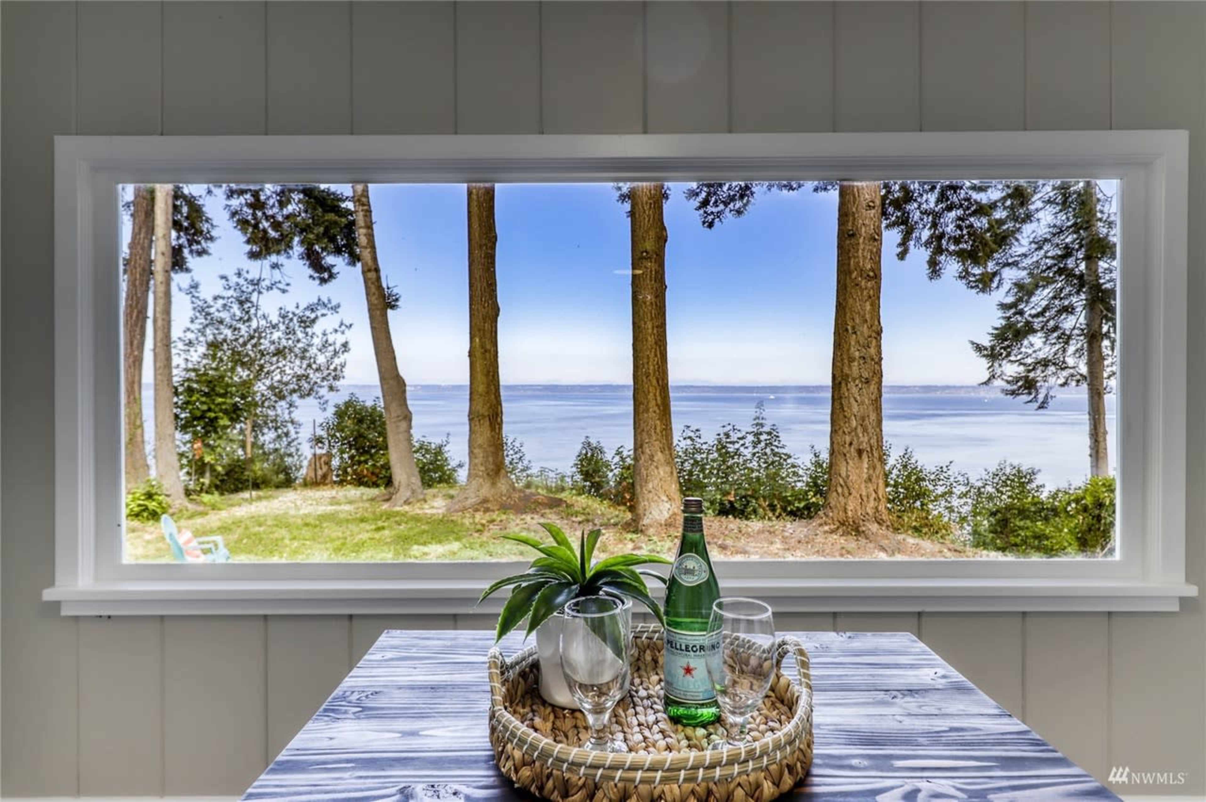 A large window with a view of trees and a body of water overlooking a landscape.