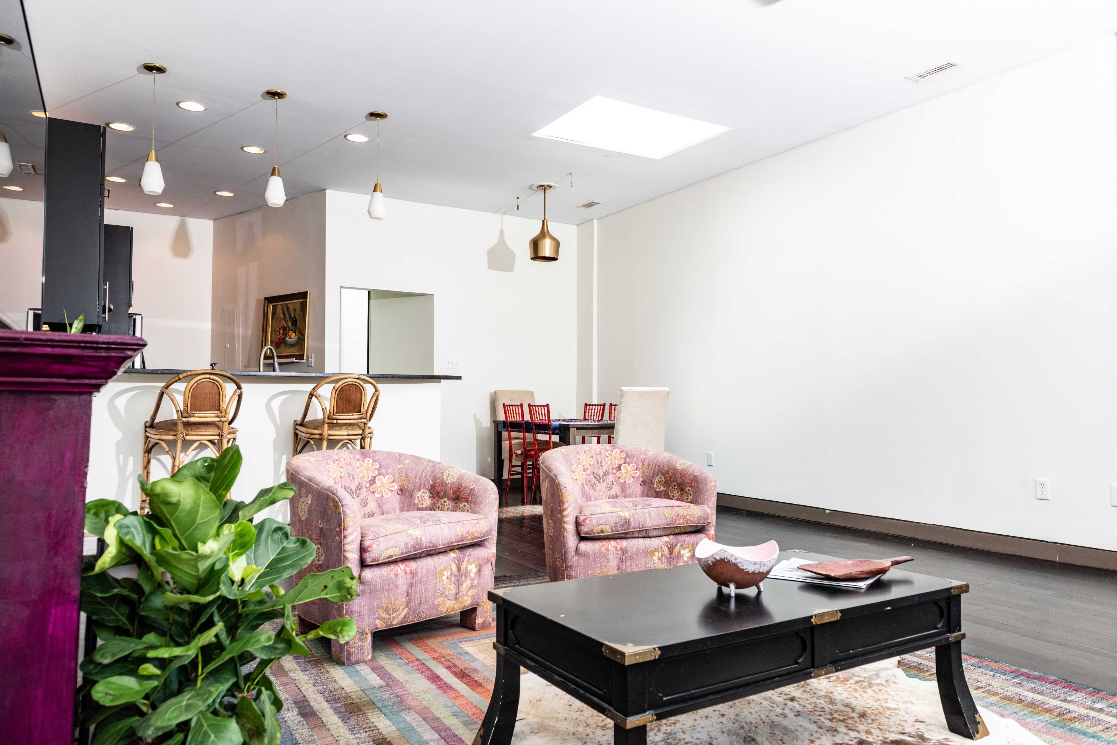 A modern living space with two floral-patterned armchairs, a coffee table, and a glimpse of a kitchen area in the background.