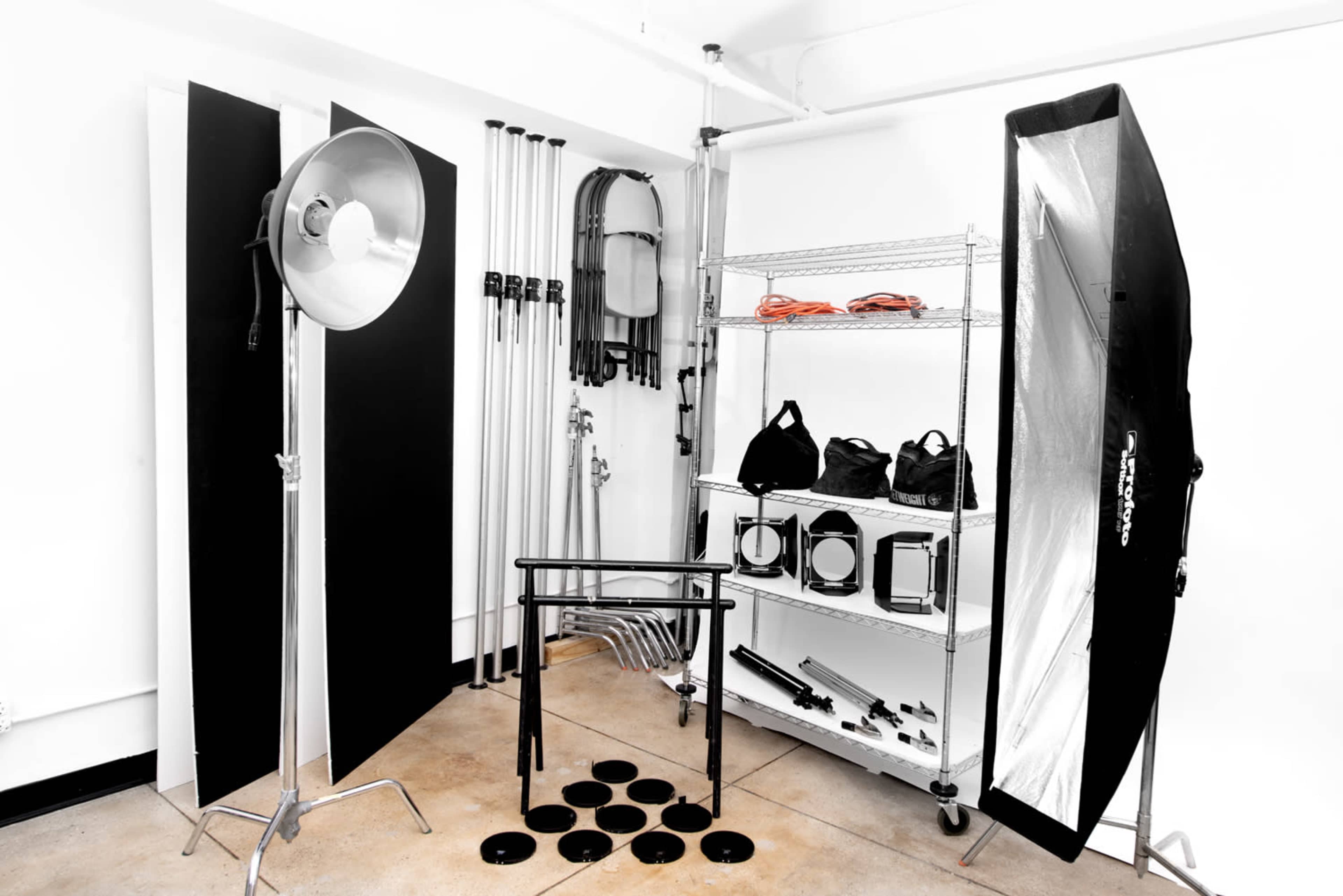 A photography studio setup with lighting equipment, backdrops, and various accessories organized on shelves.